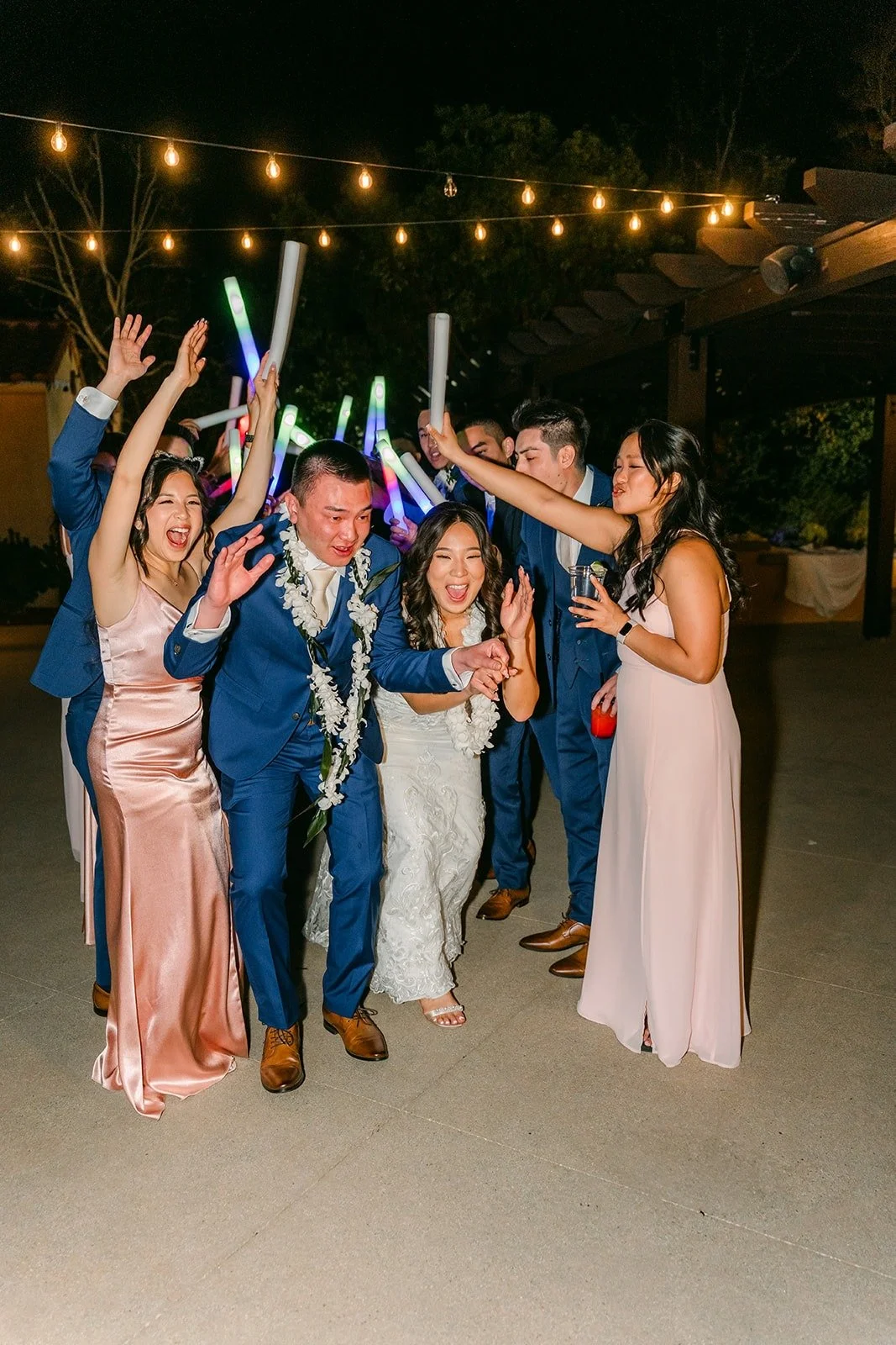 Kelli and Alex celebrating with friends waving light up foam sticks, photographed by One and Only Production