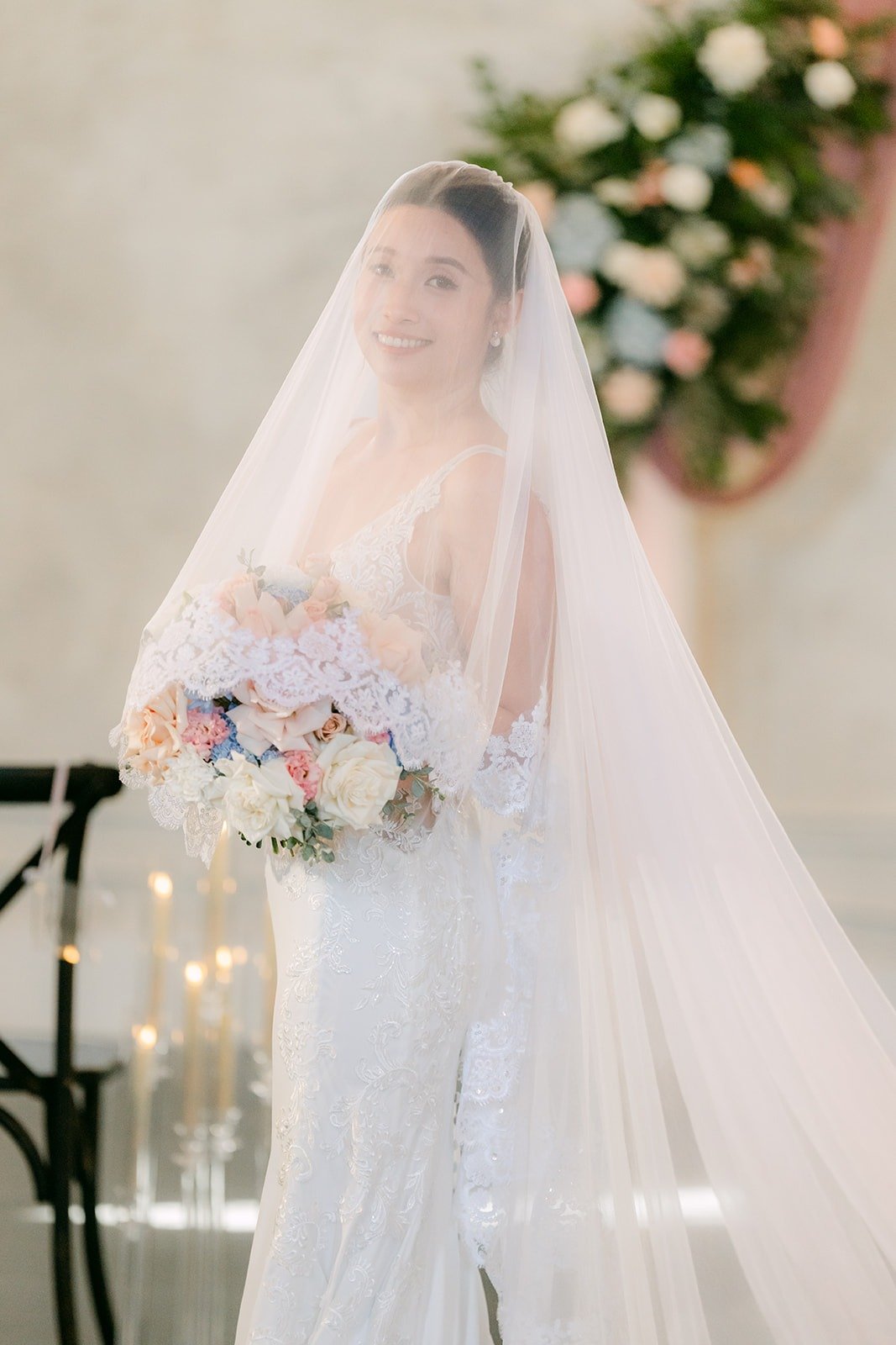 Elisa holds her bouquet under a long cathedral veil