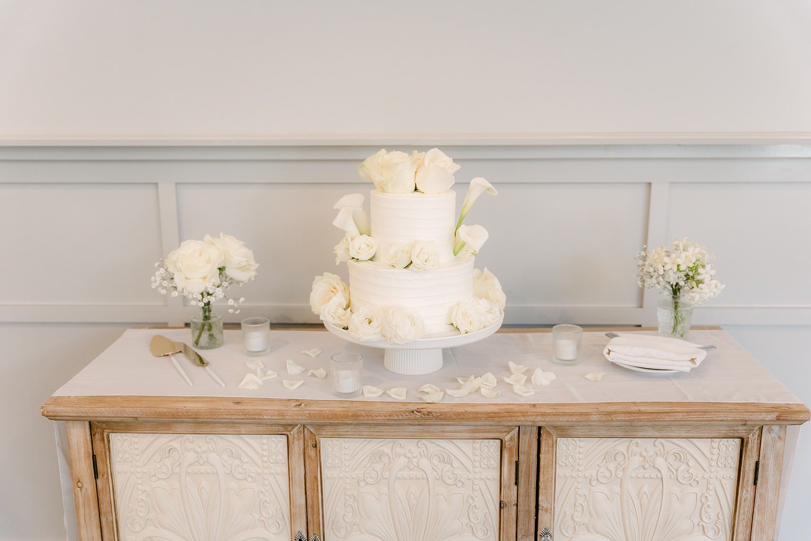 The white wedding cake with white roses on a wooden table