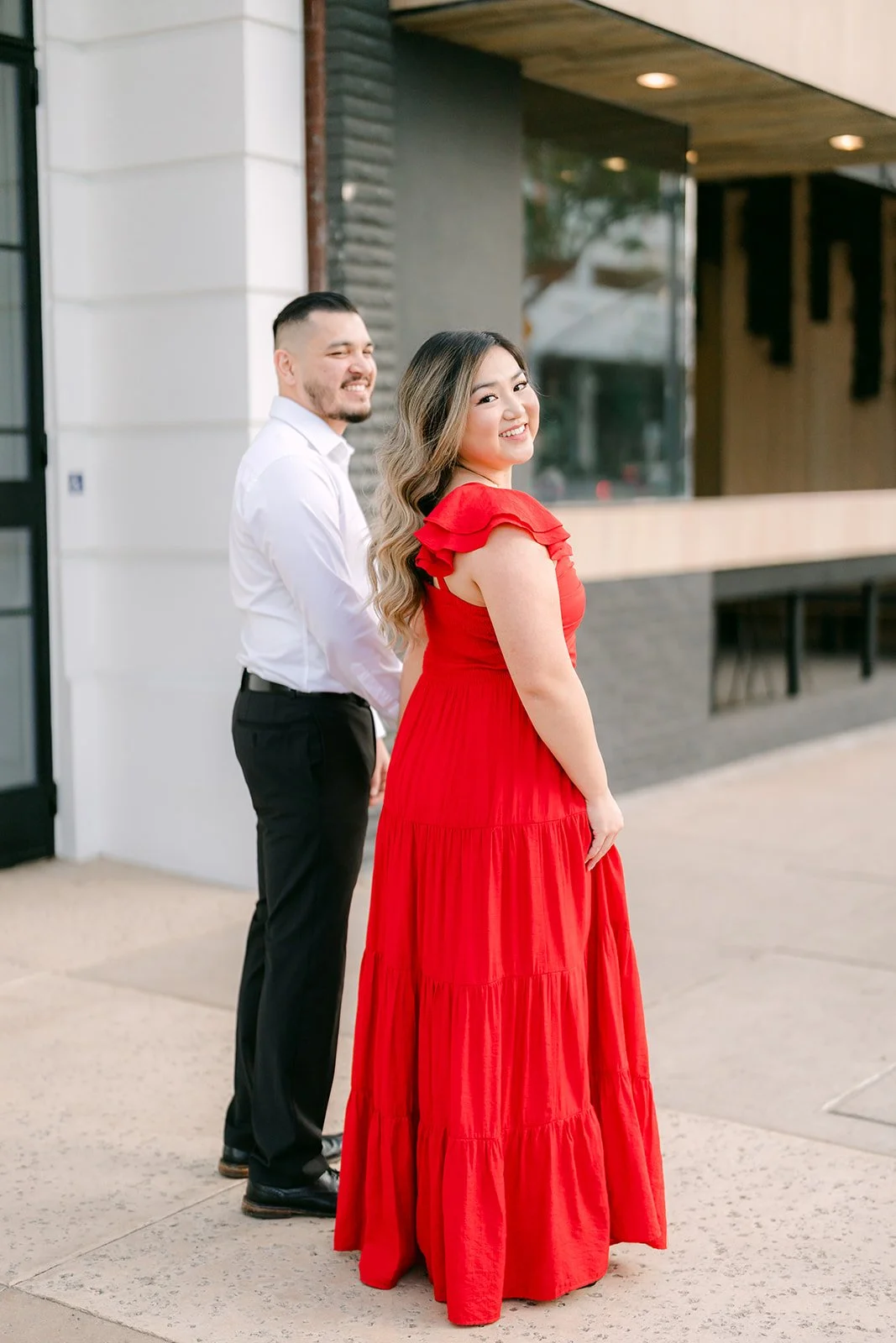 Linh in her red dress smiles beside Ankush outside the restaurant.
