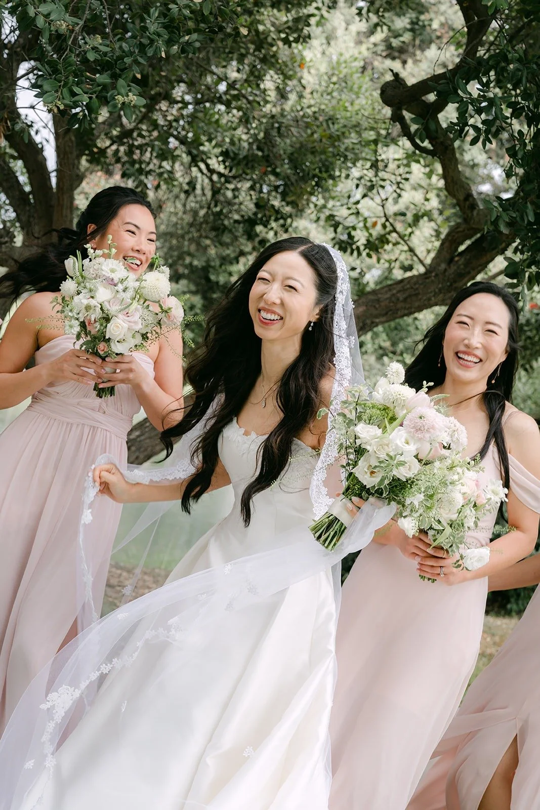Kristine laughing with her bridesmaids and their bouquets
