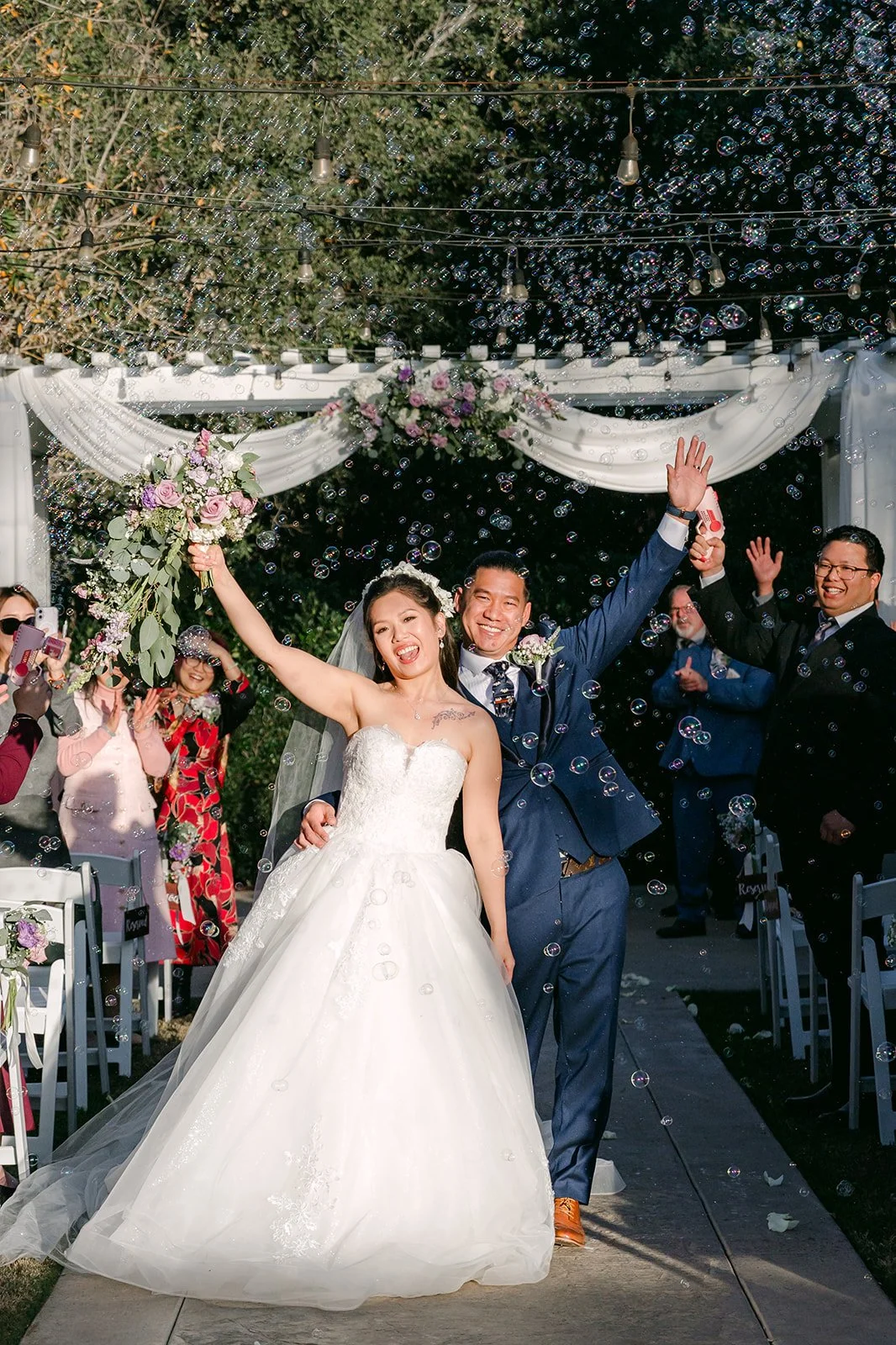 Kate and Michael cheering as they walk back up the aisle, photographed by One and Only Production.