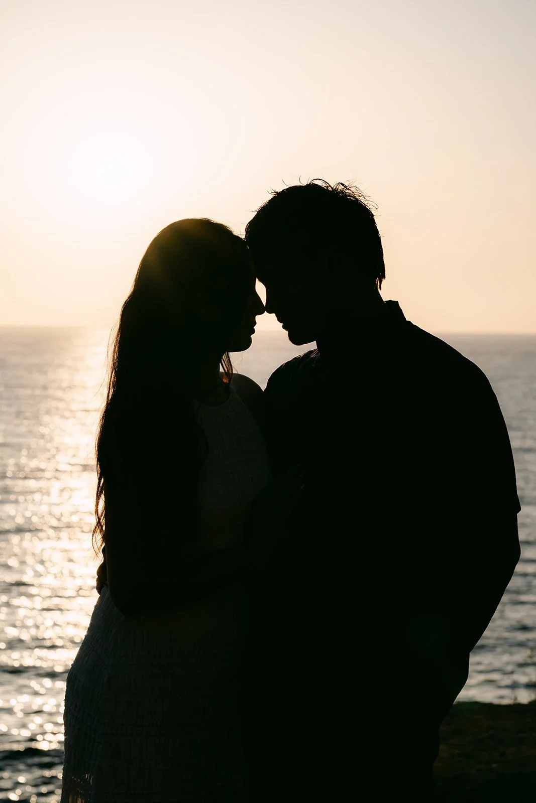 Victoria and Andrew lean in together in silhouette at sunset, photographed by One and Only Production.