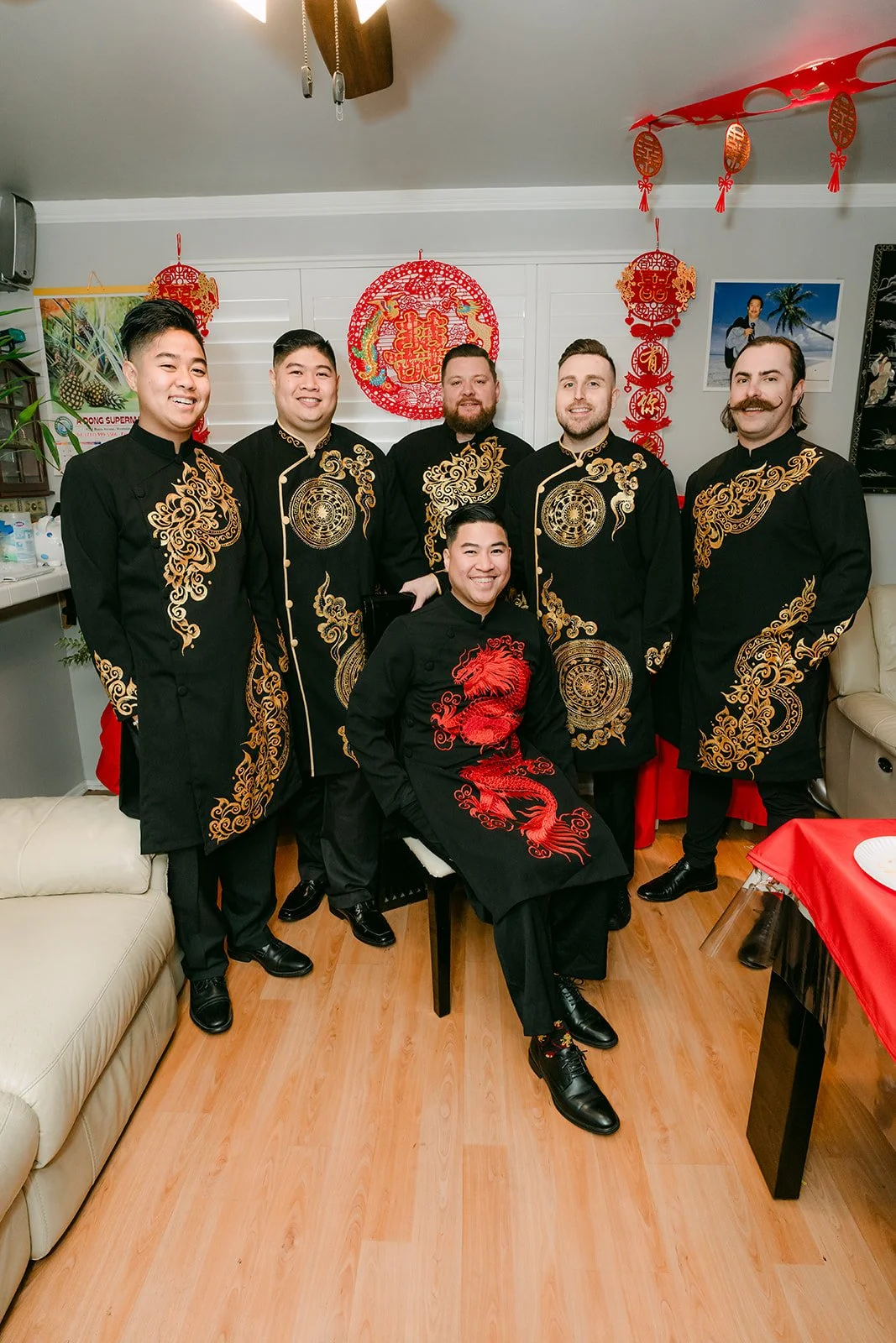 A groom and his groomsmen in matching black changshan posing together.
