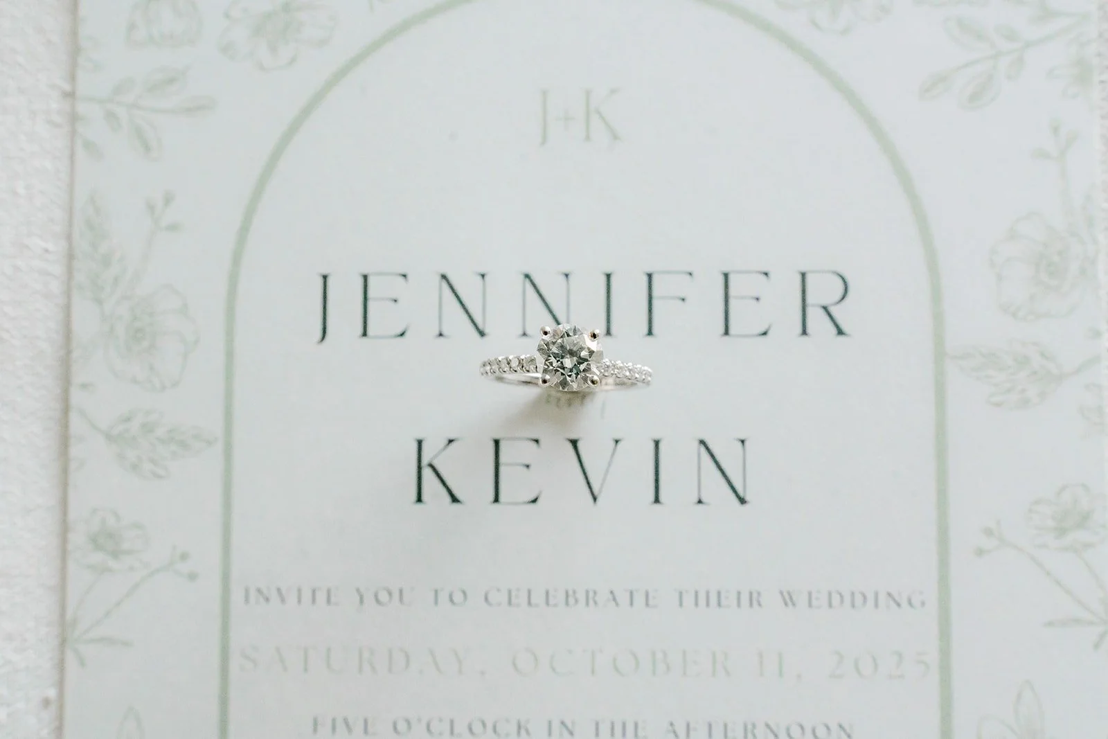 Jennifer and Kevin's arched invitation with an engagement ring set on top