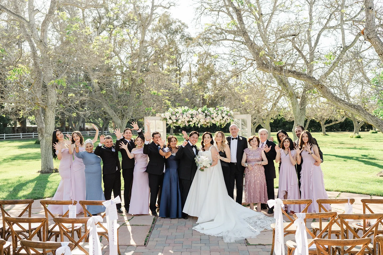 Wedding party celebrating with the couple at the ceremony arch