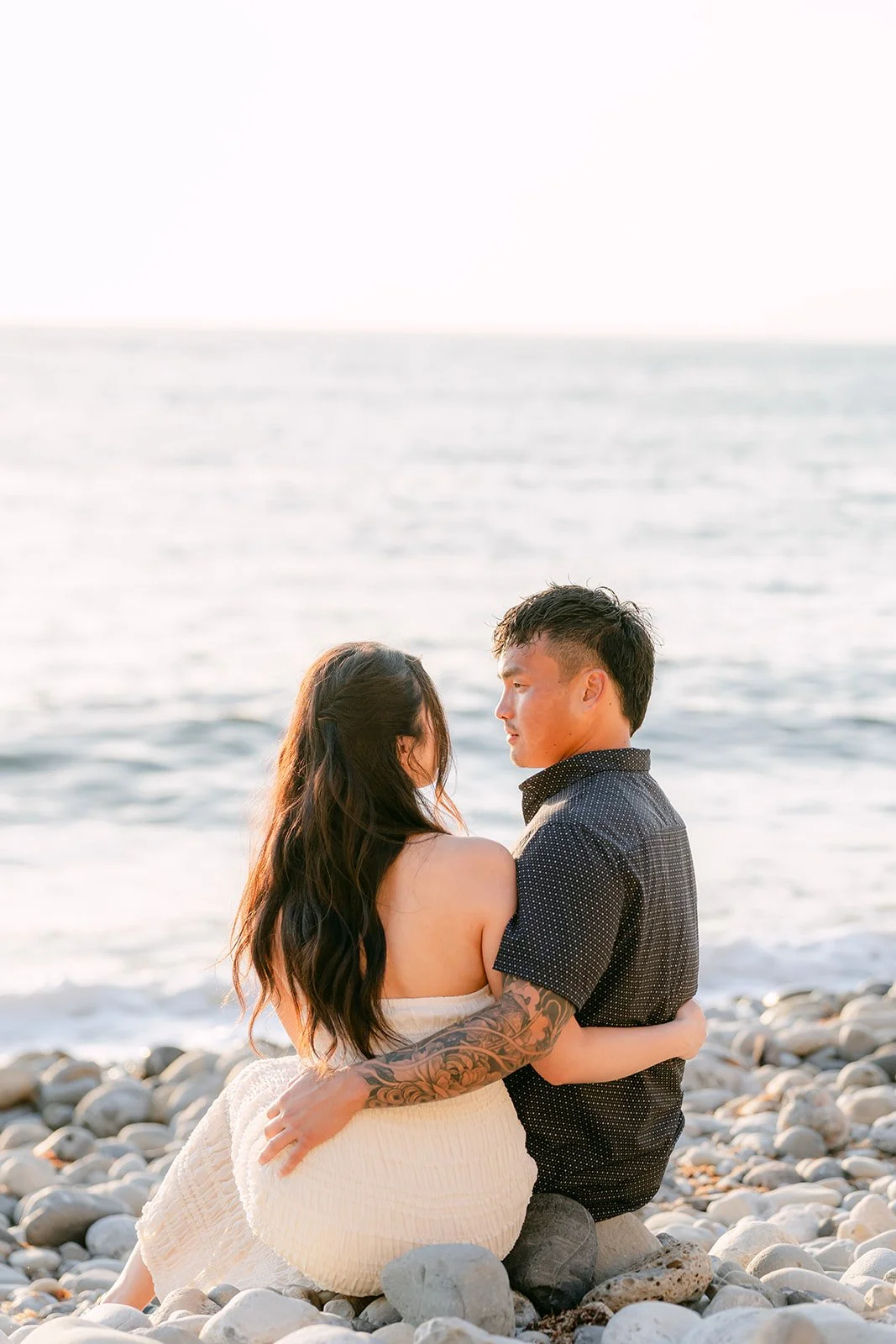 Victoria and Andrew laugh together on the rocks in golden light.