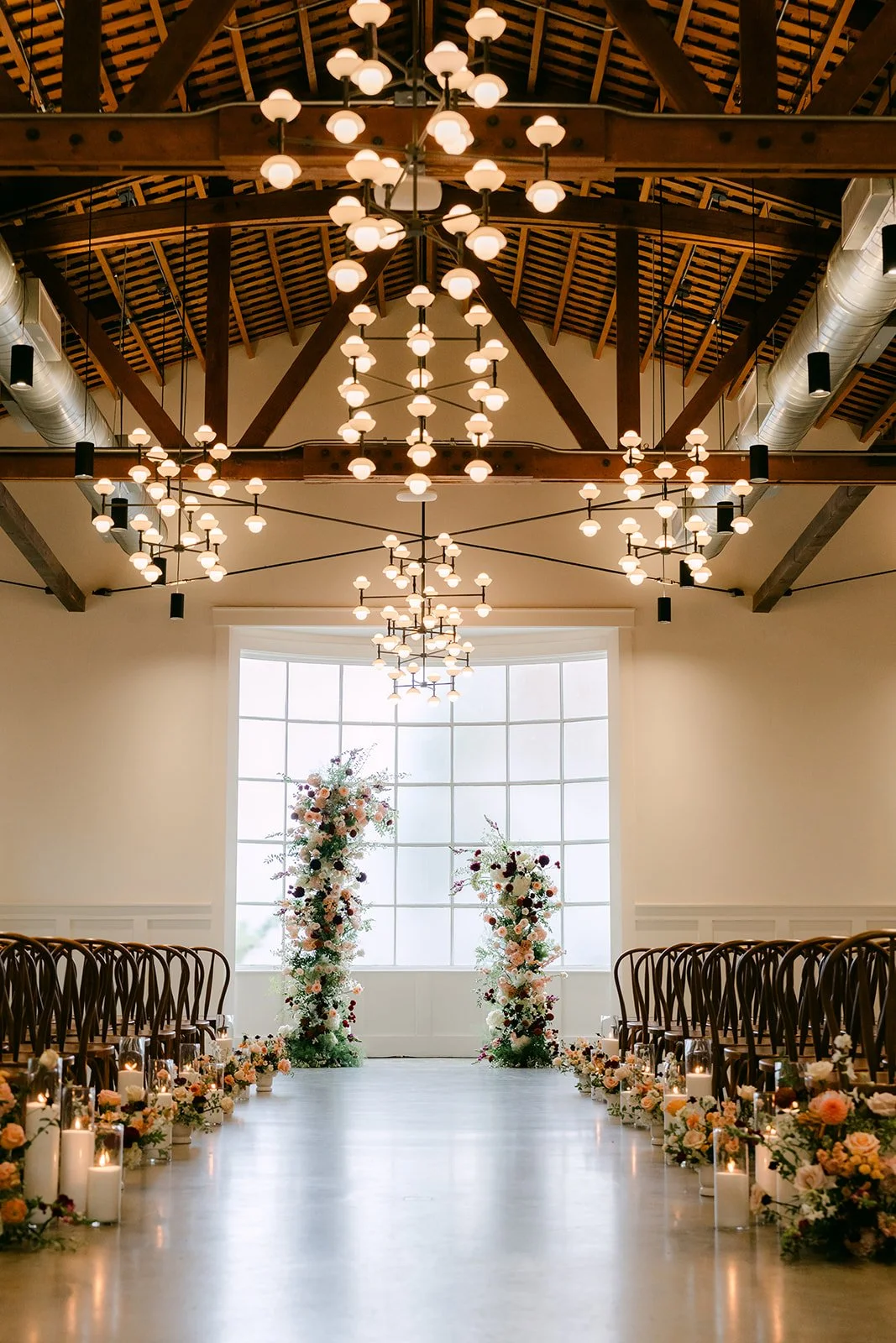 The ceremony aisle at The Richland lined with florals under wood beams and chandeliers.
