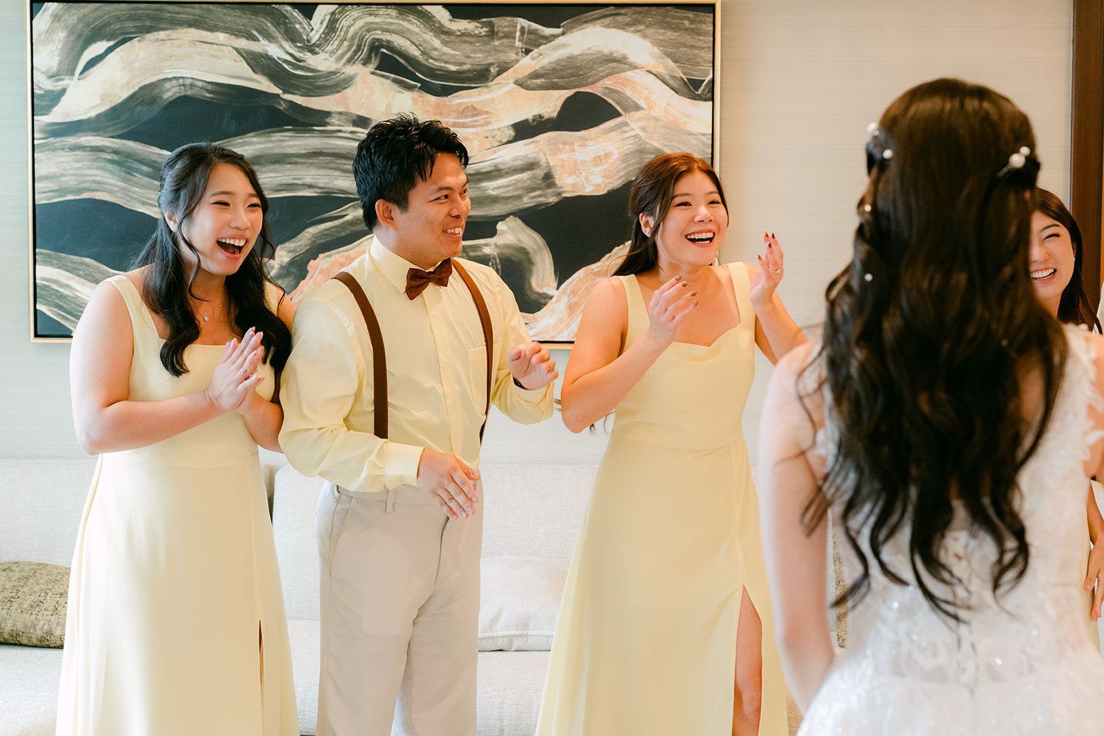 Jenny's bridesmaids in butter yellow reacting as they see her in her gown.