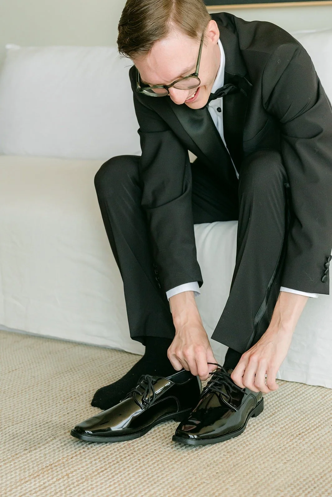 Nik tying his shoes in his black tuxedo