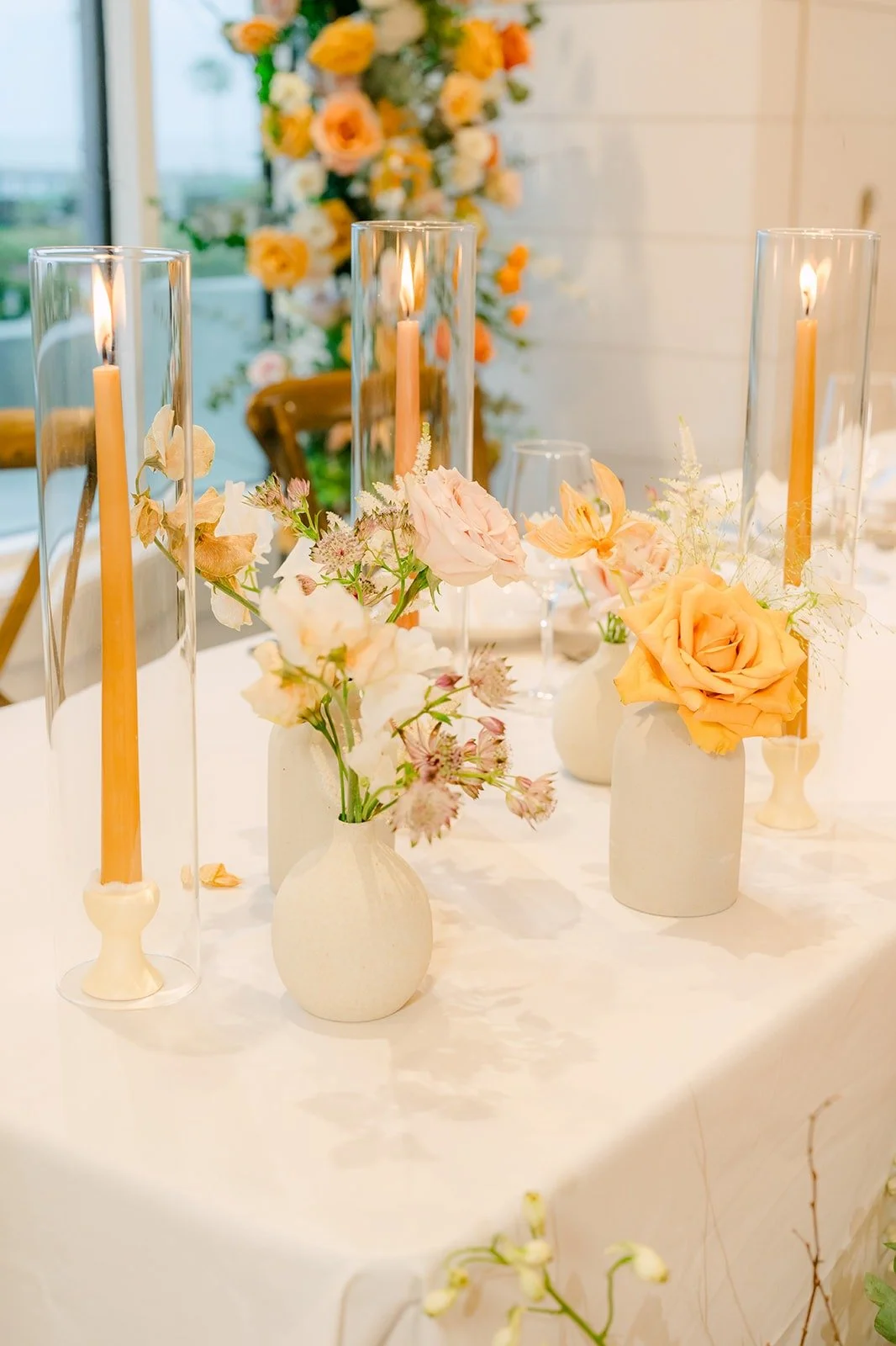 Taper candles and peach roses in bud vases along the tables