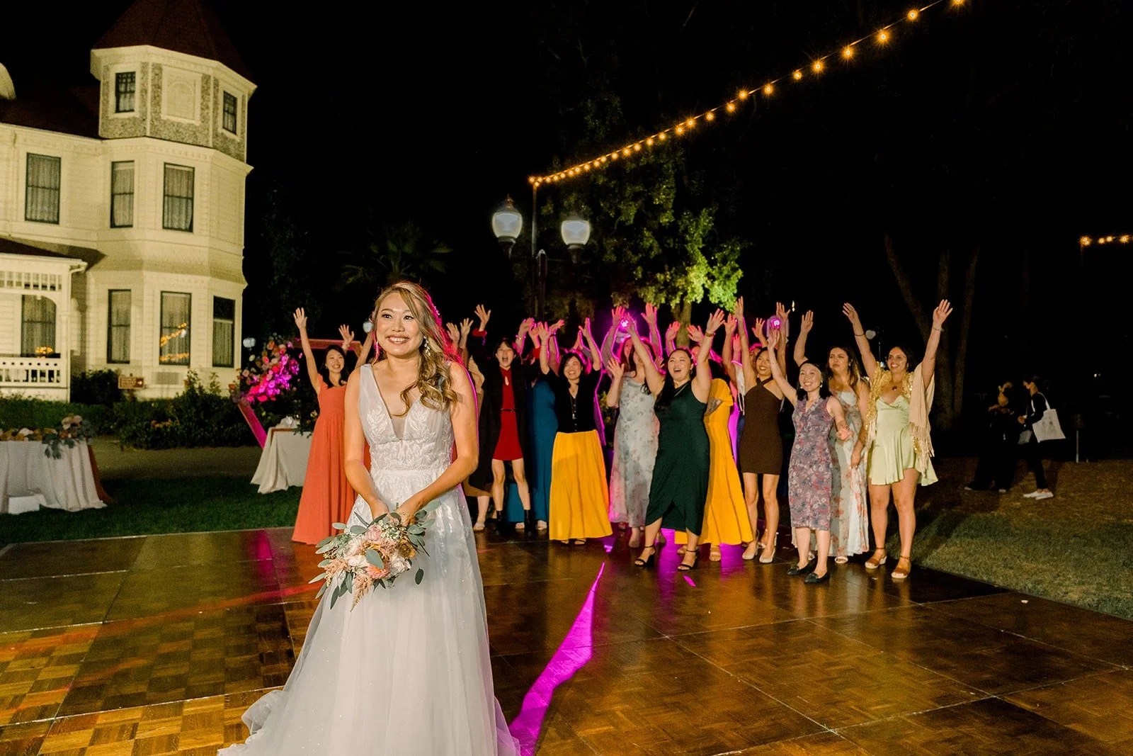 Ariel tossing her bouquet under the string lights