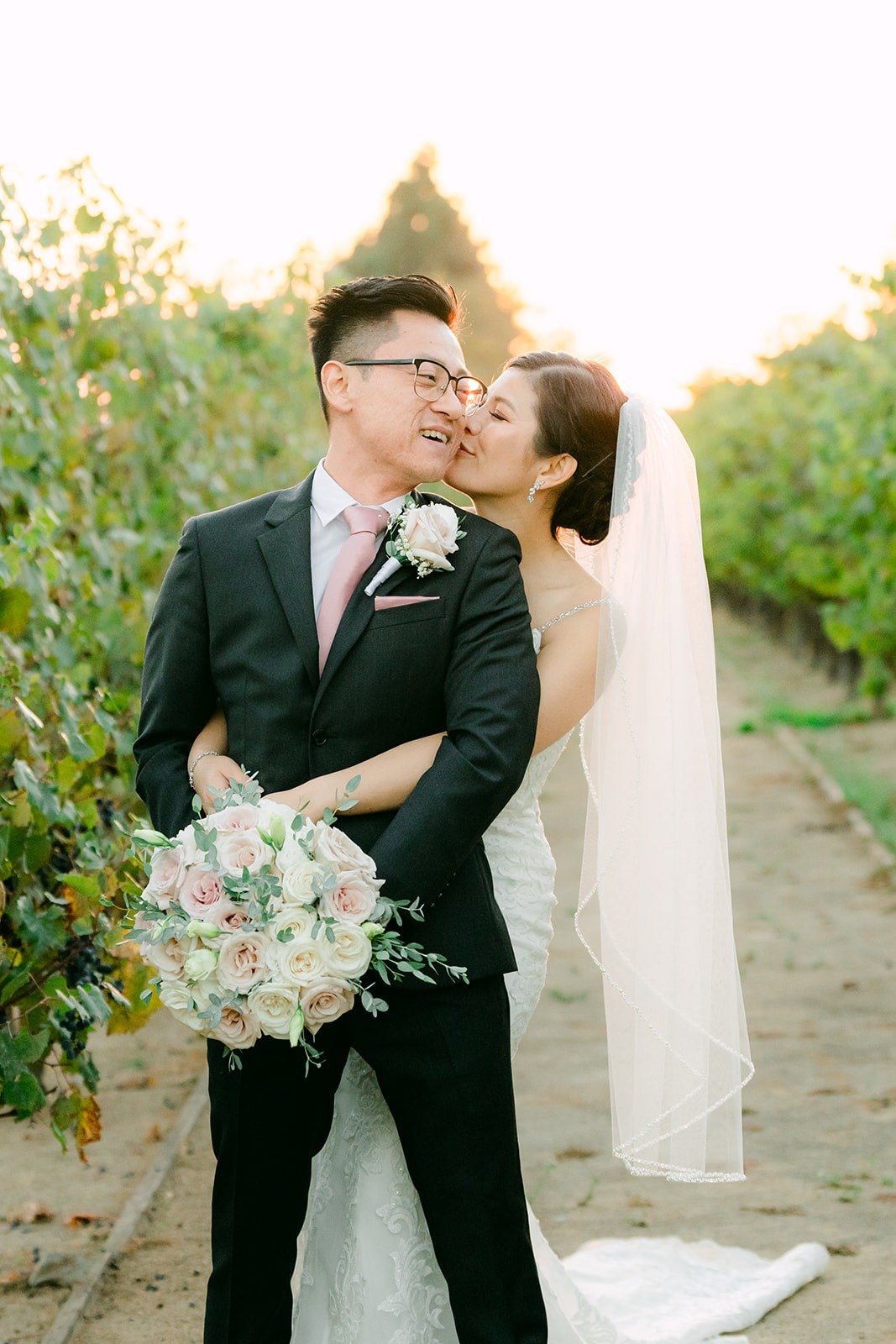 Xuemin and Alex kissing in the vineyard at sunset