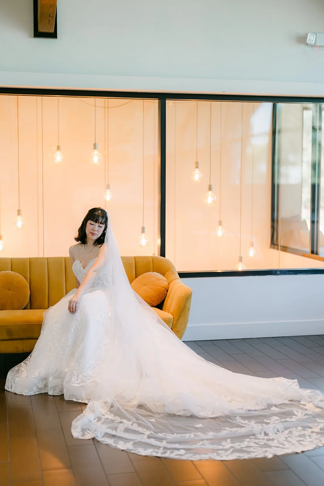 Vivian on a mustard velvet sofa with her train spread across the floor