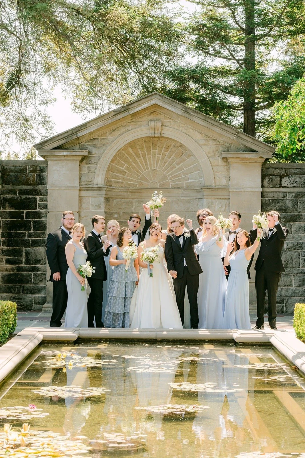 Wedding party lined up behind the reflecting pool at Greystone Mansion