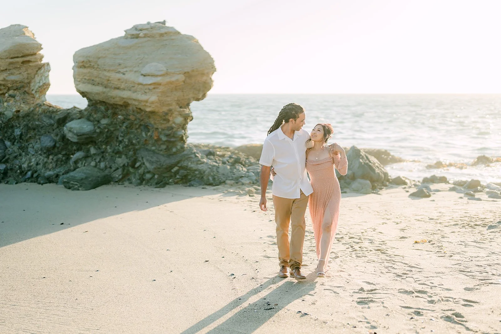 Amy and Michael walking hand in hand along the shoreline.