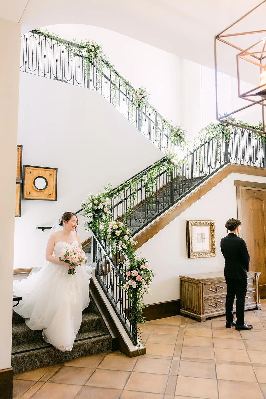 Bride descending the staircase toward the groom for their first look at Vellano Estate