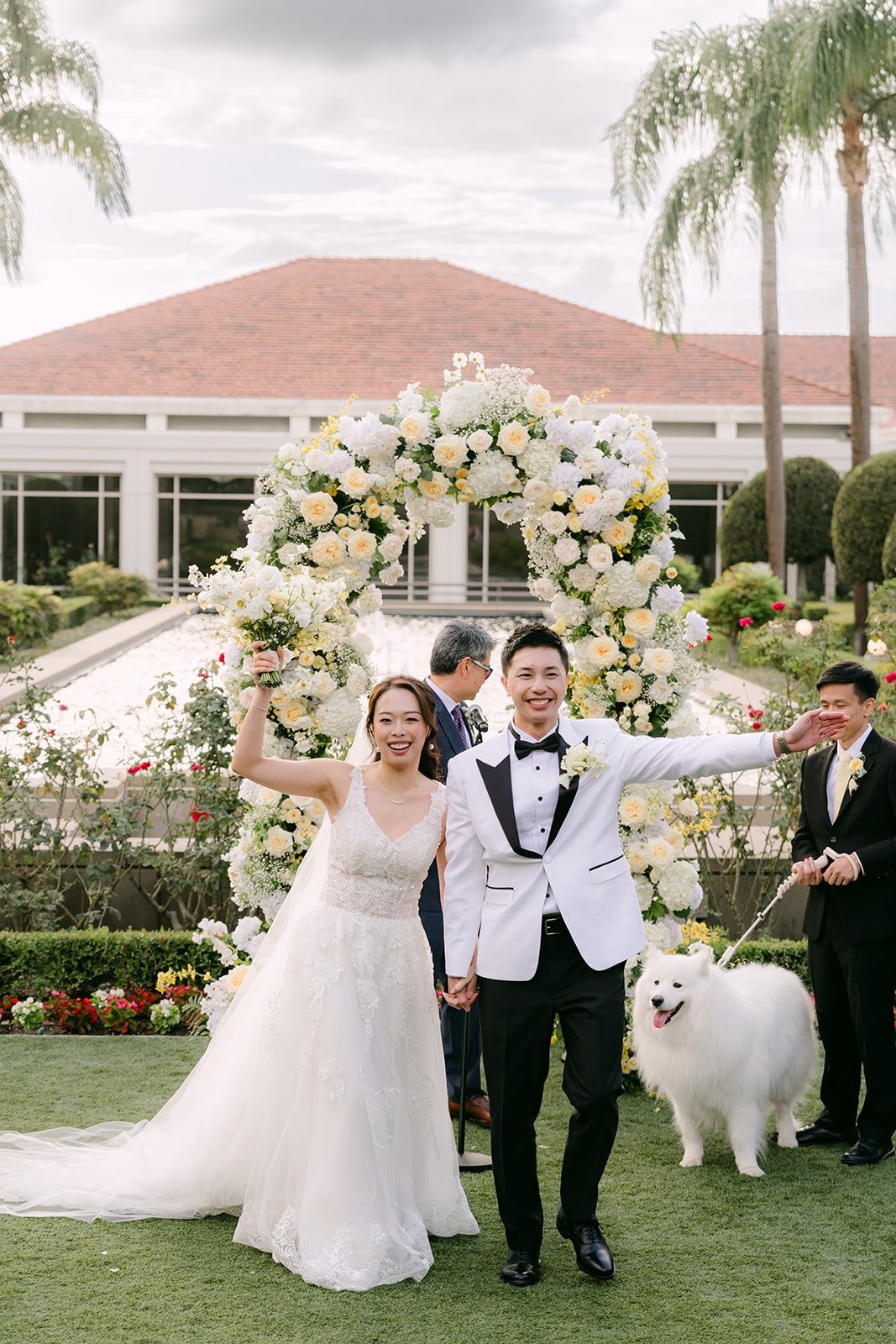 Jenny, Ryan and Snowball under the floral arch after the ceremony.