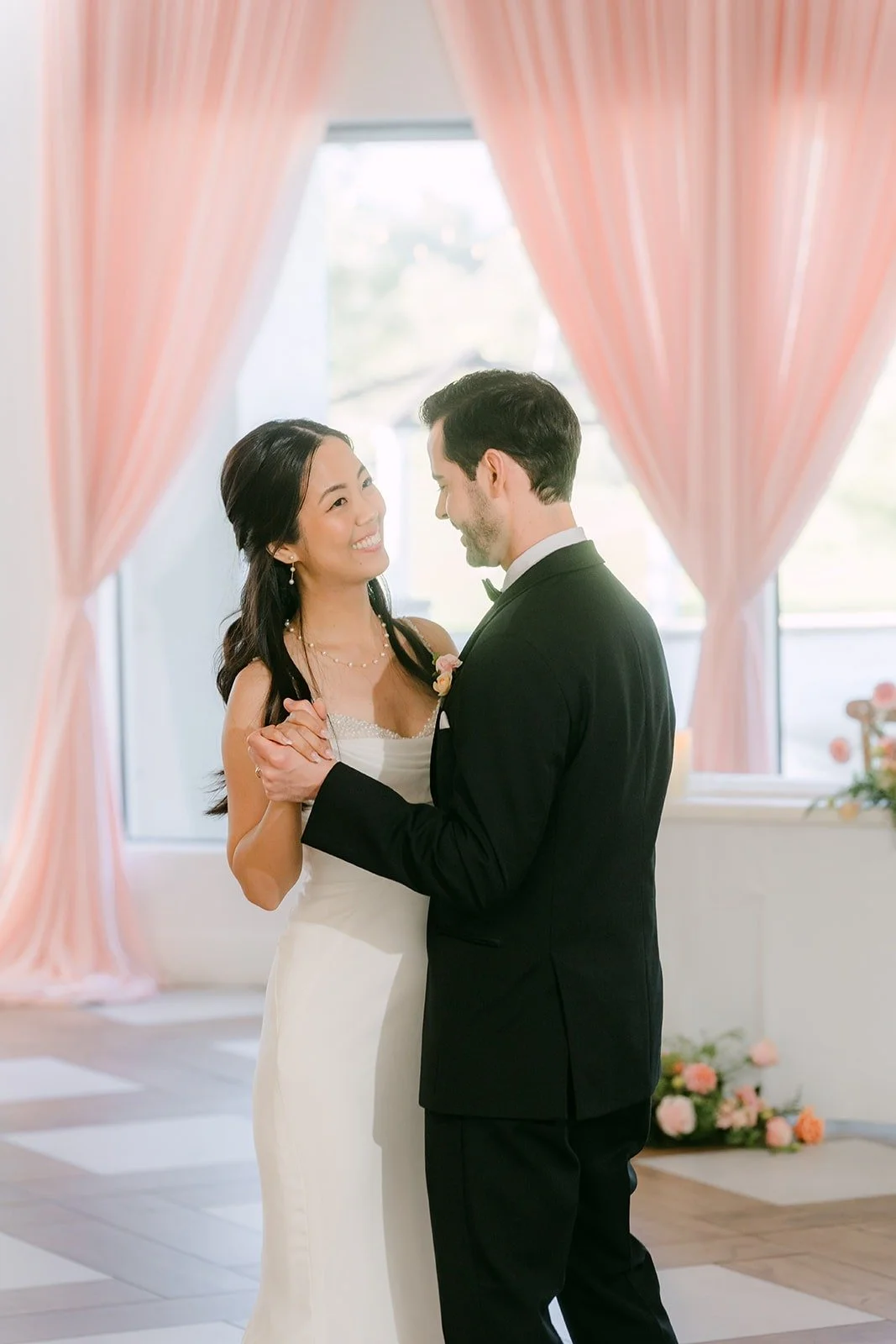 Stephanie and Kevin dancing close in front of the blush drapes