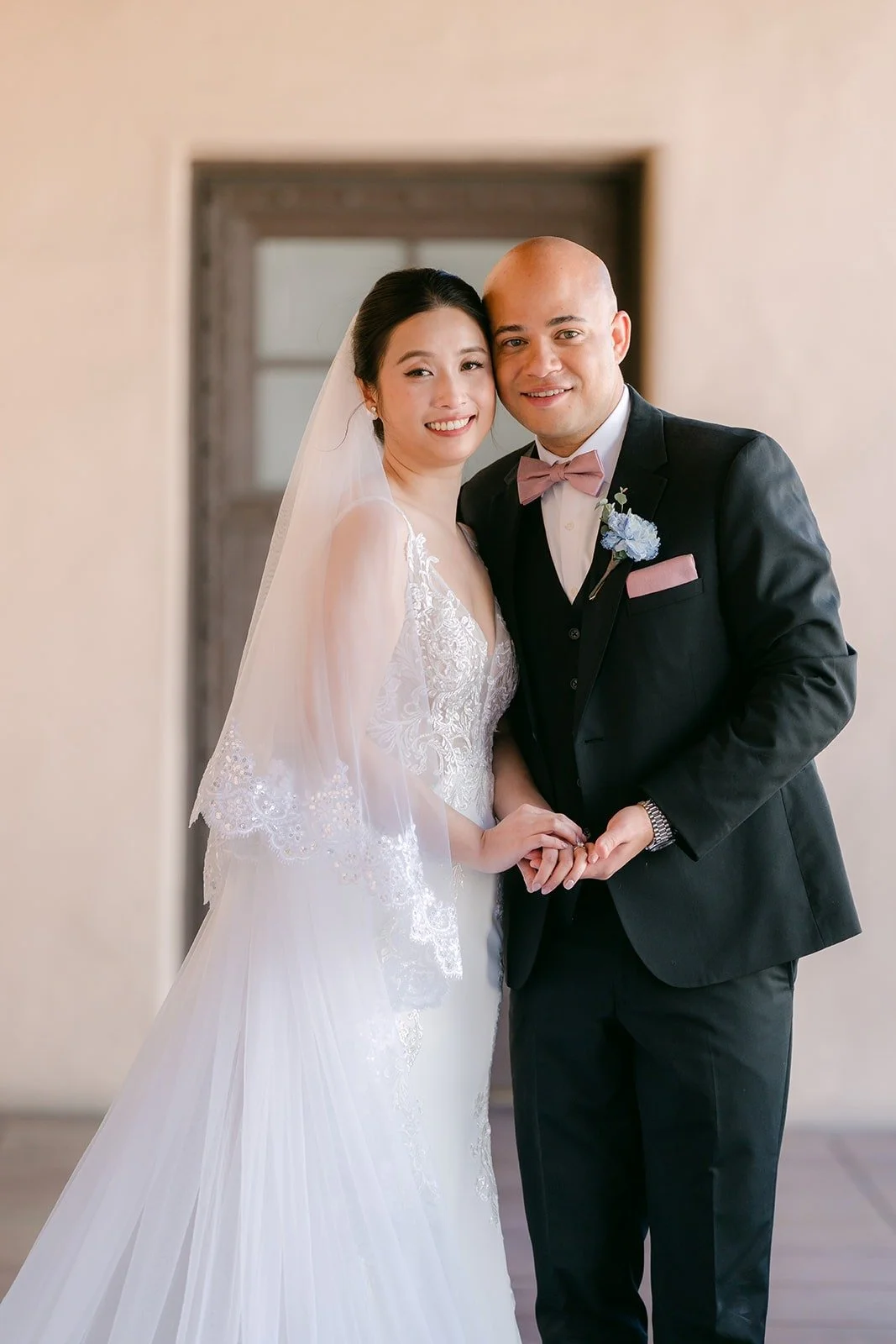Elisa and Brandon smile side by side in front of a wooden door
