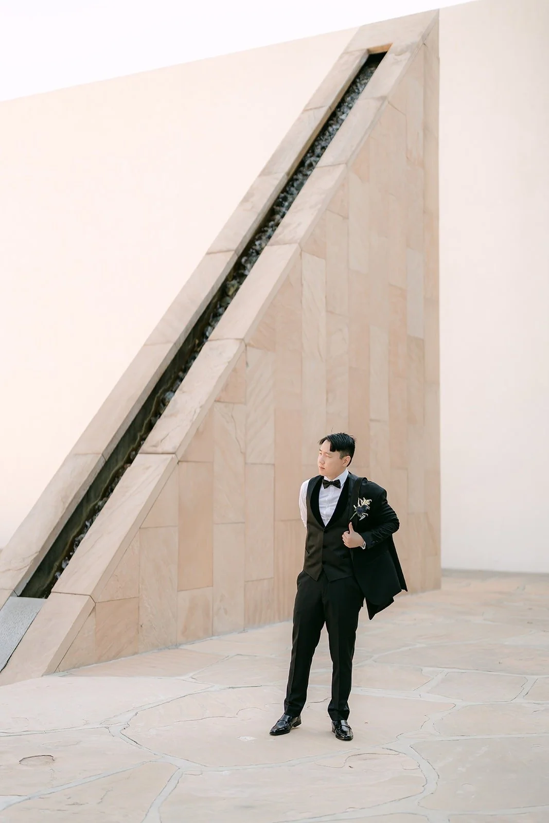 James in his black tuxedo beside the angled Noguchi Garden wall
