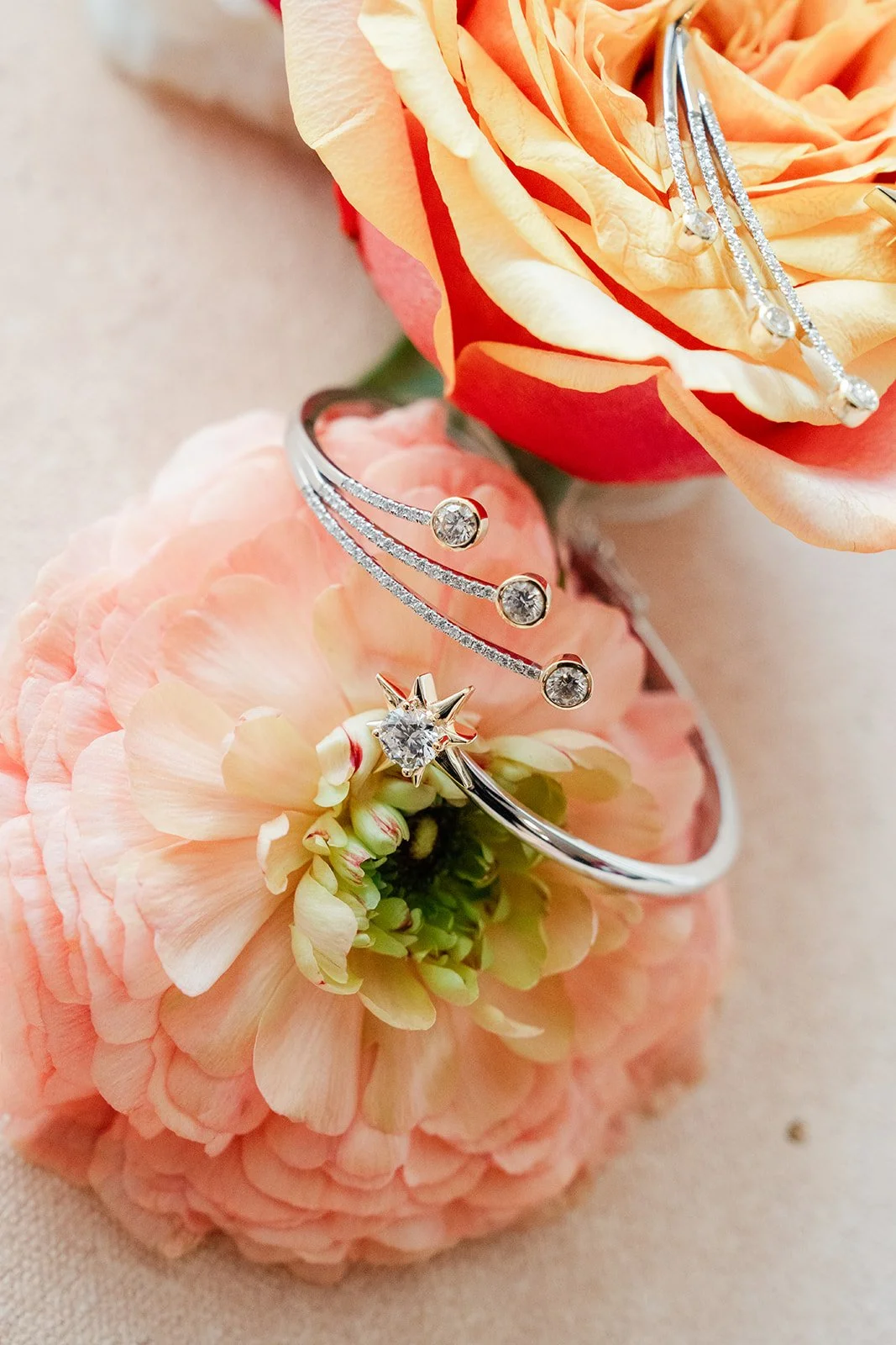 Rings resting on a pink ranunculus in the flat lay.