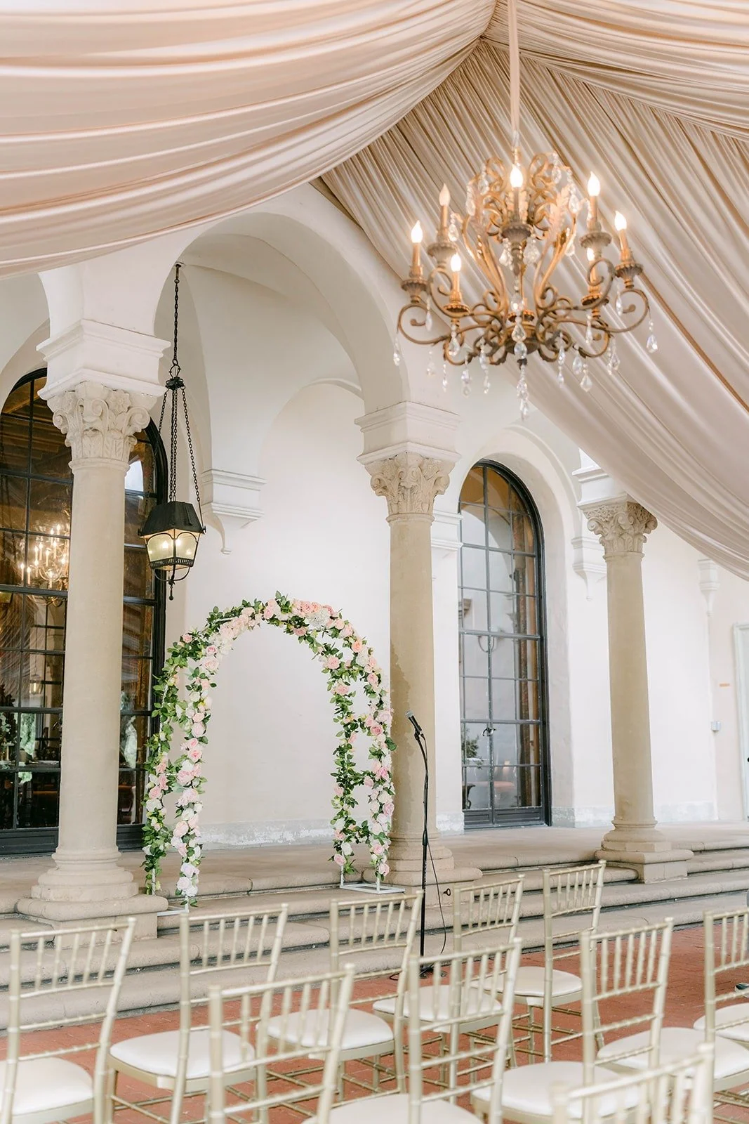 The rose arch at the front of the aisle under a chandelier, photographed by One and Only Production