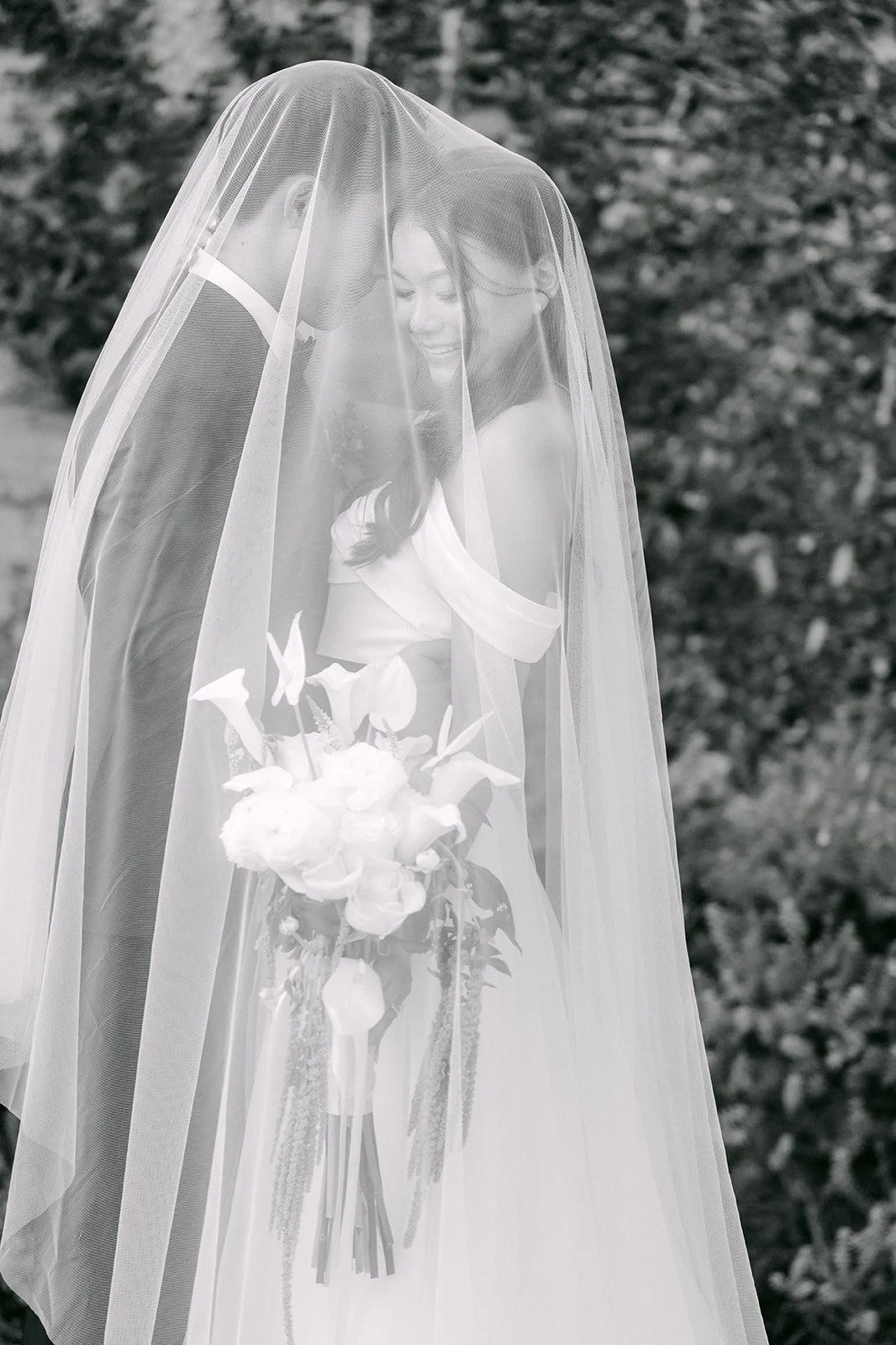 Black and white portrait of Jadee under her veil with a white bouquet