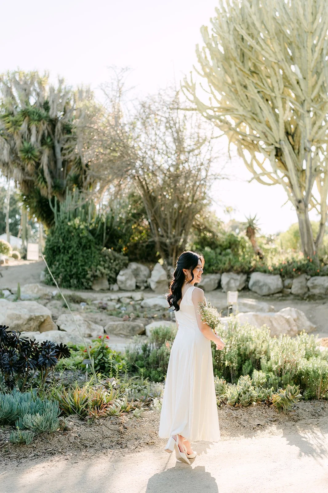 Kim walking along a path lined with drought-tolerant plants and trees.