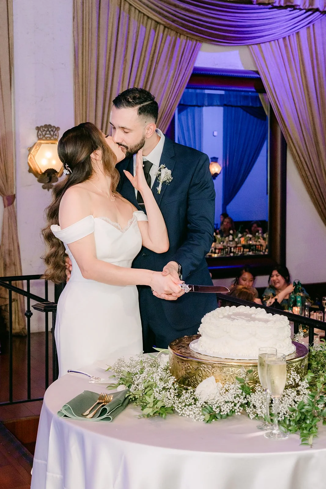 Mariana and Danny kissing beside their cake