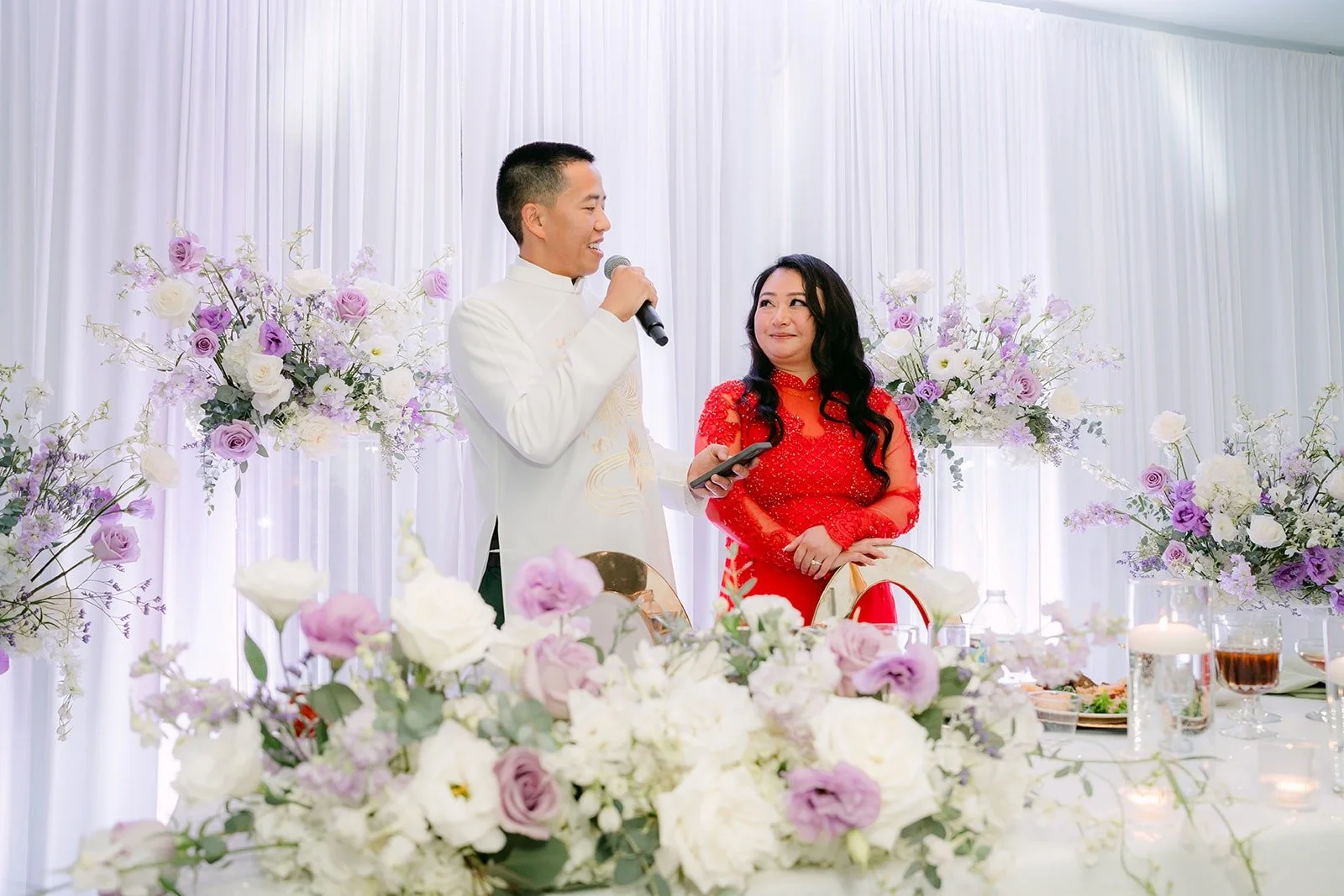 Kevin in his white ao dai and Jennifer in red thank their guests from the sweetheart table