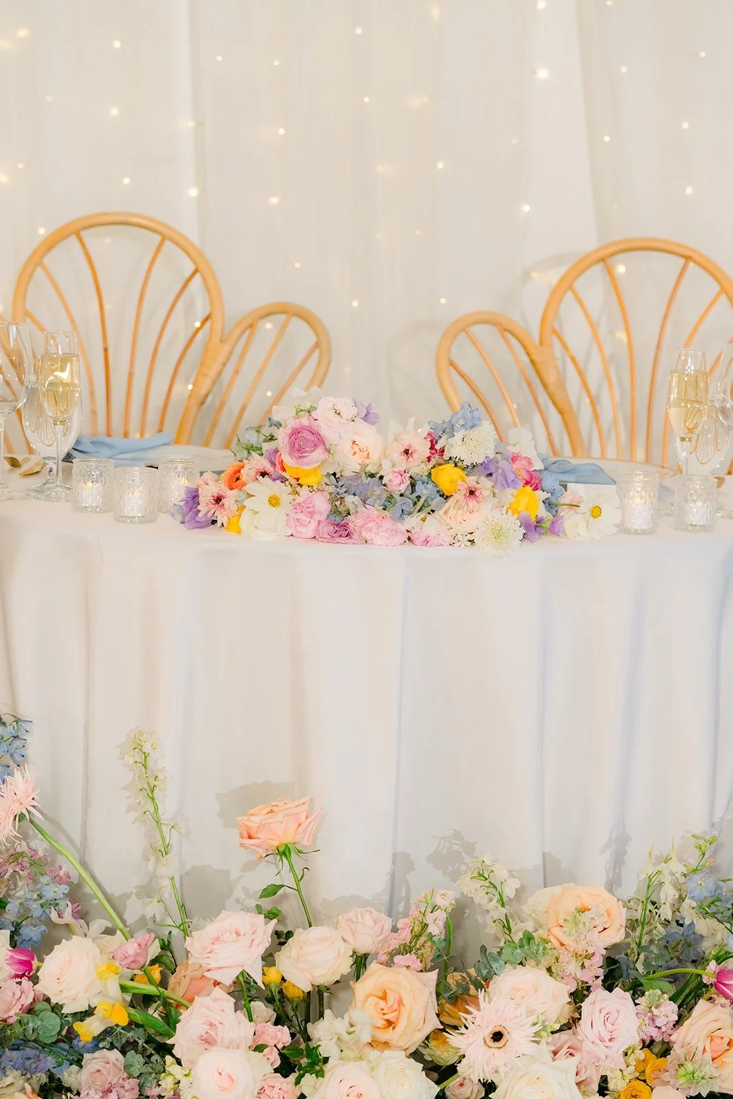 The sweetheart table with rattan chairs and a garland of pastel florals