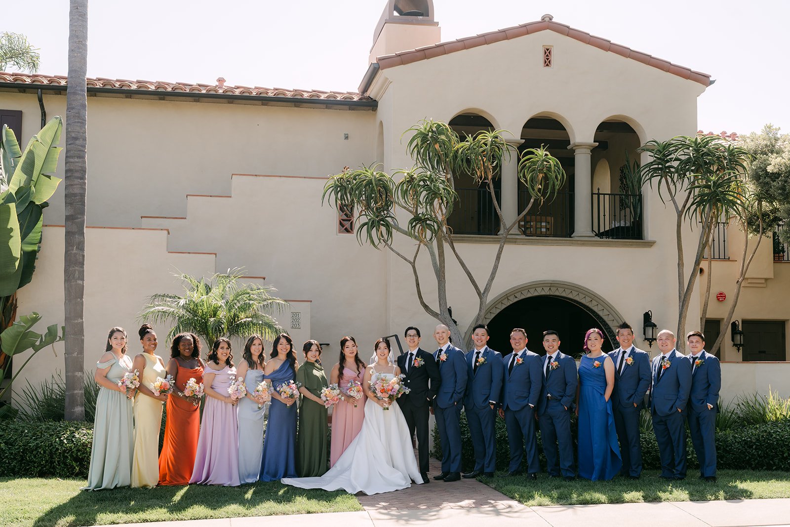 The full wedding party in colorful gowns and blue suits