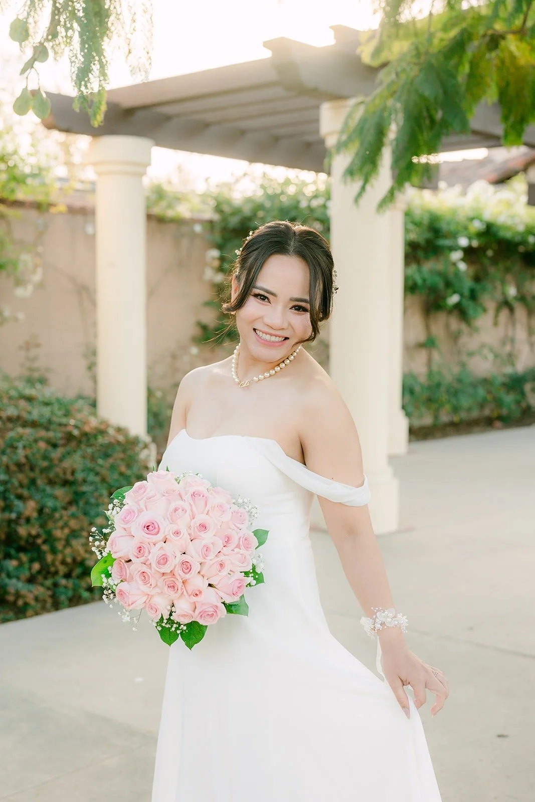 Ivy with her pink rose bouquet under the colonnade at Wedgewood Aliso Viejo