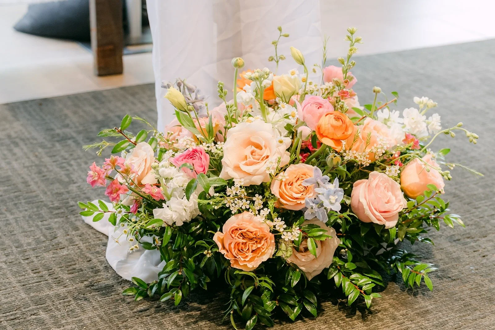 A low arrangement of peach roses and pink blooms at the end of the aisle