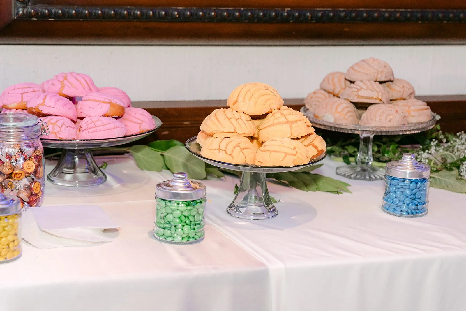 Conchas and pan dulce on cake stands at the dessert table, photographed by One and Only Production