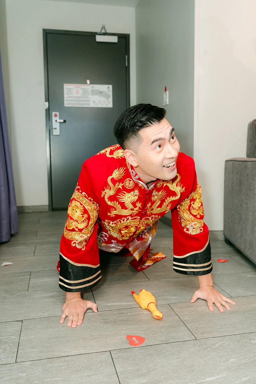 A groom in his red changshan doing push ups on the floor for the bridesmaids.