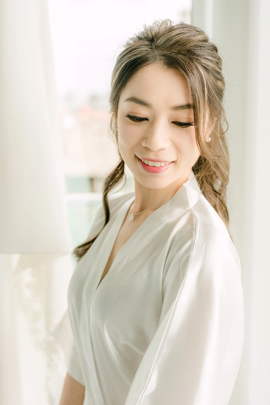 Angela smiling in her satin robe with her hair pinned half up
