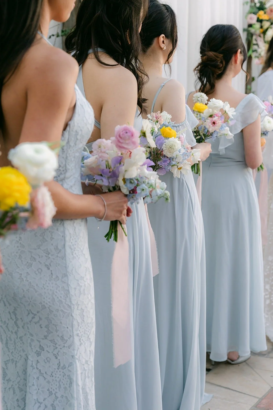 Bridesmaids holding their pastel bouquets during the ceremony