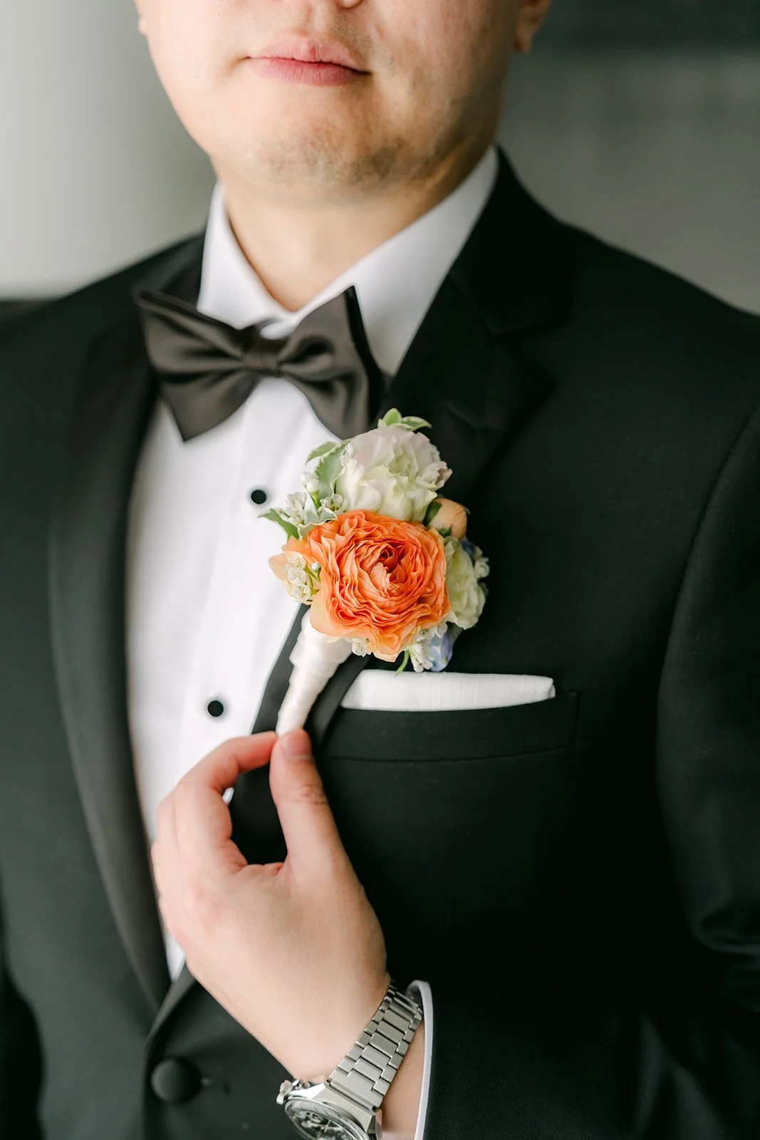 Close detail of San's peach boutonniere and bow tie, photographed by One and Only Production.