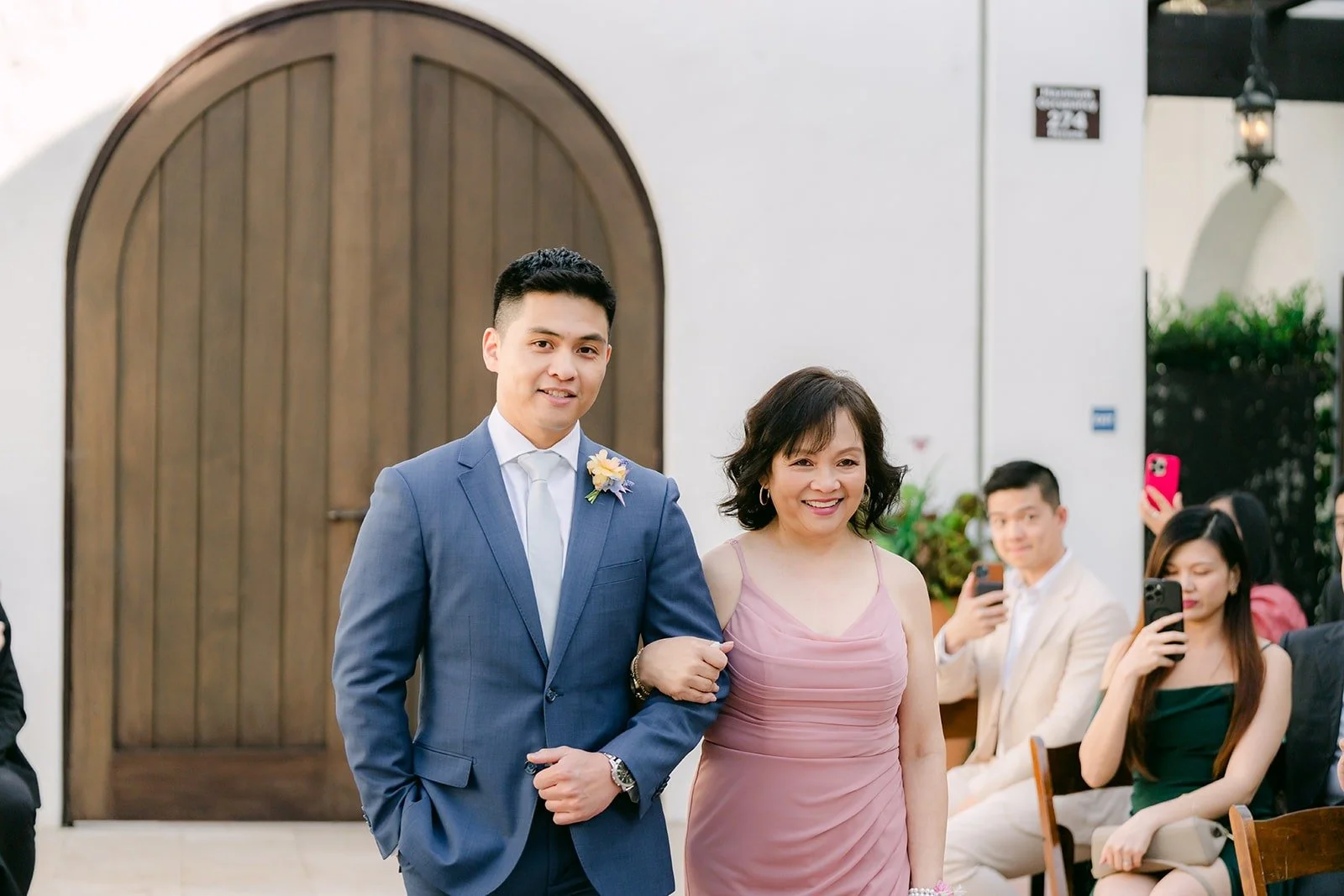 Jerrick walking a family member down the aisle in the La Ventura courtyard