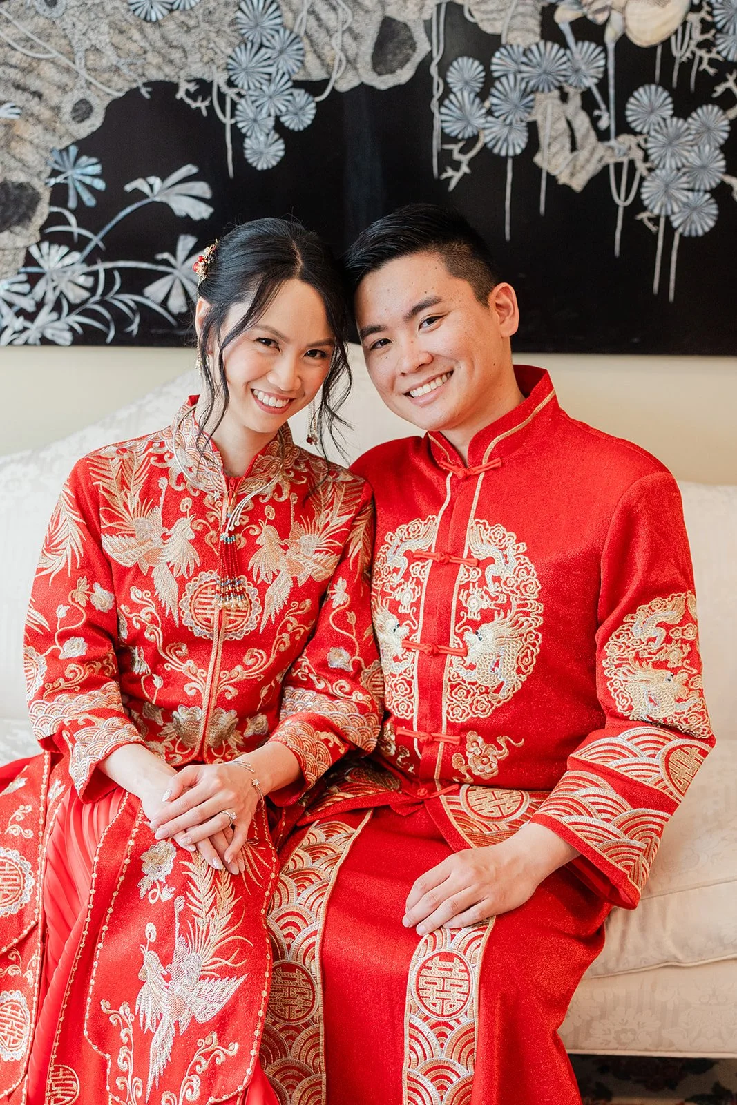 A bride and groom in red qun kwa and changshan sitting close together.