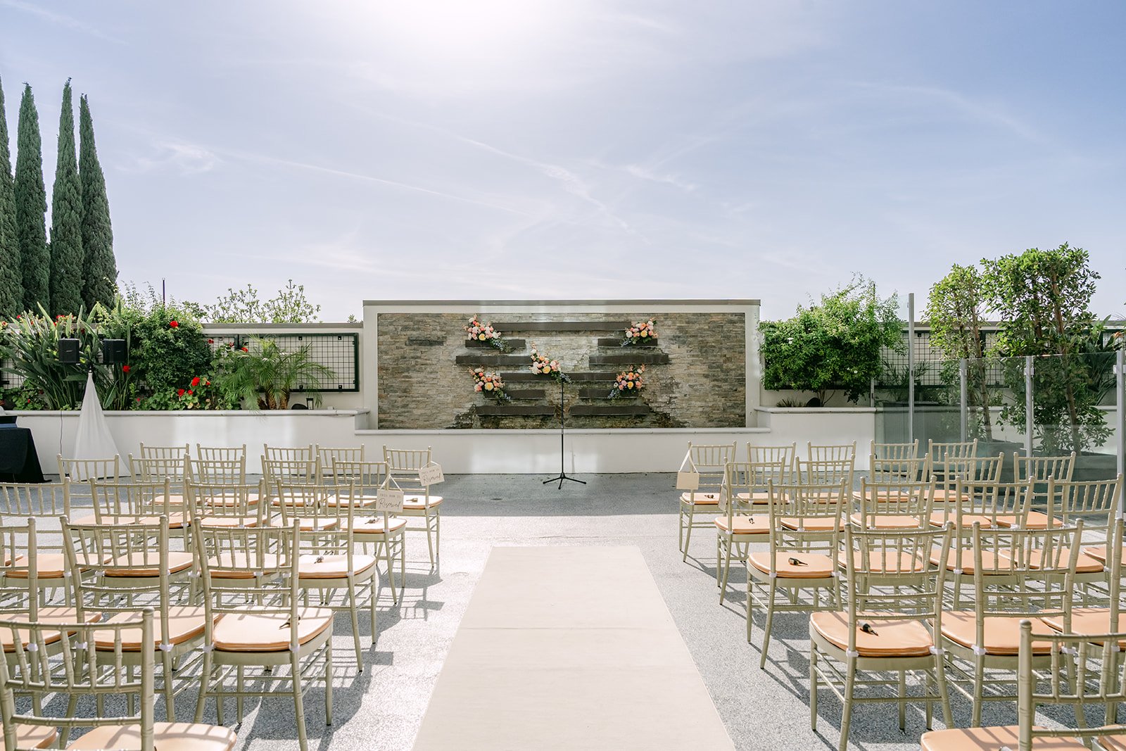 The ceremony setup on the terrace with florals at the stone wall.