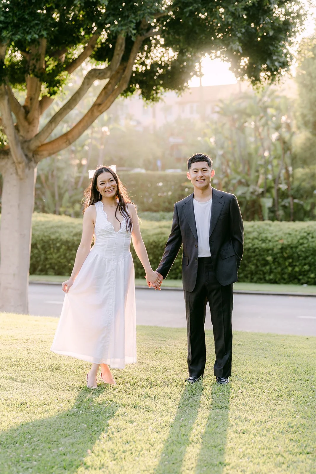Jadee and Richard walk across the lawn beneath the trees, photographed by One and Only Production.