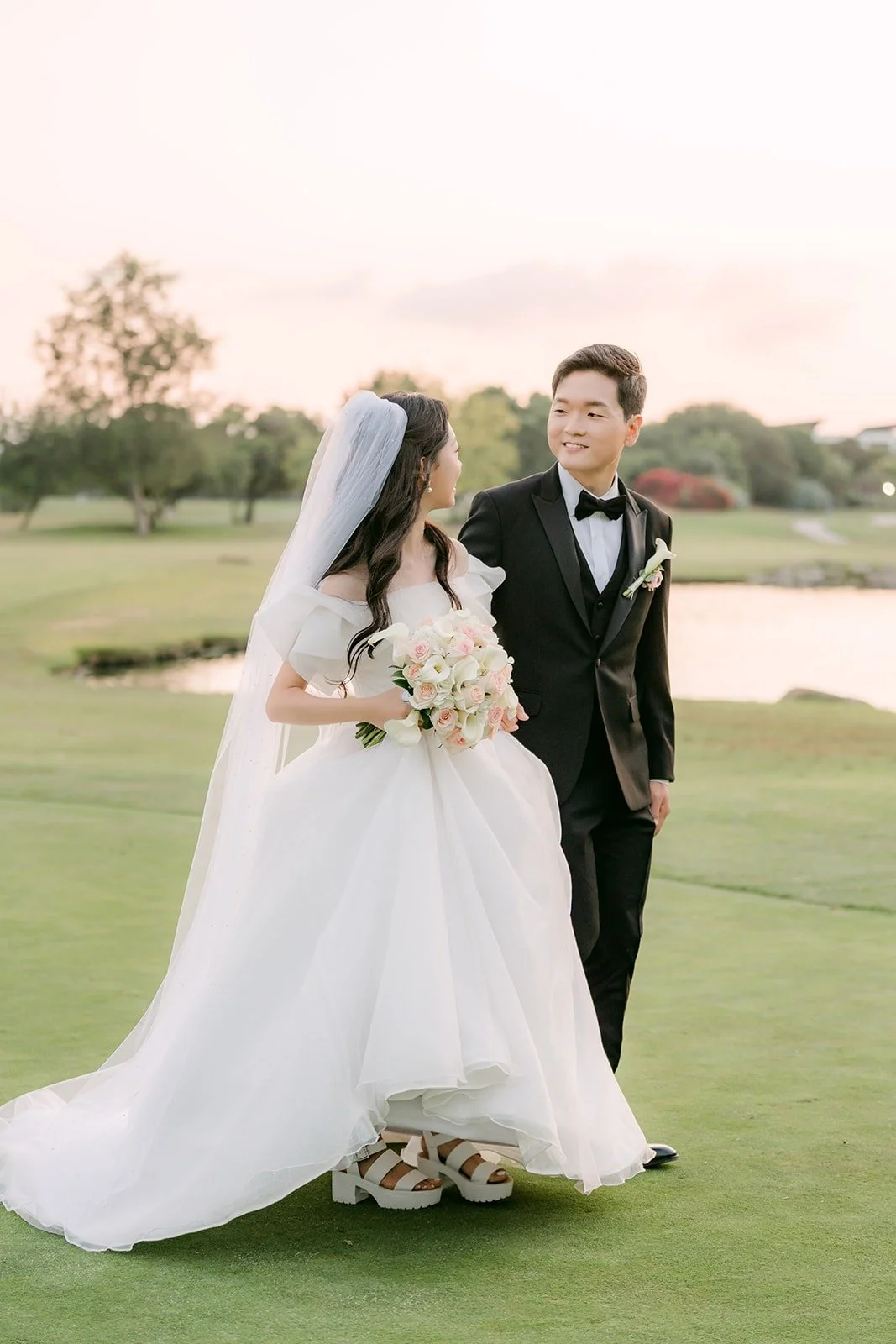 Jeannie and Eunsang on the green with the lake behind them, photographed by One and Only Production