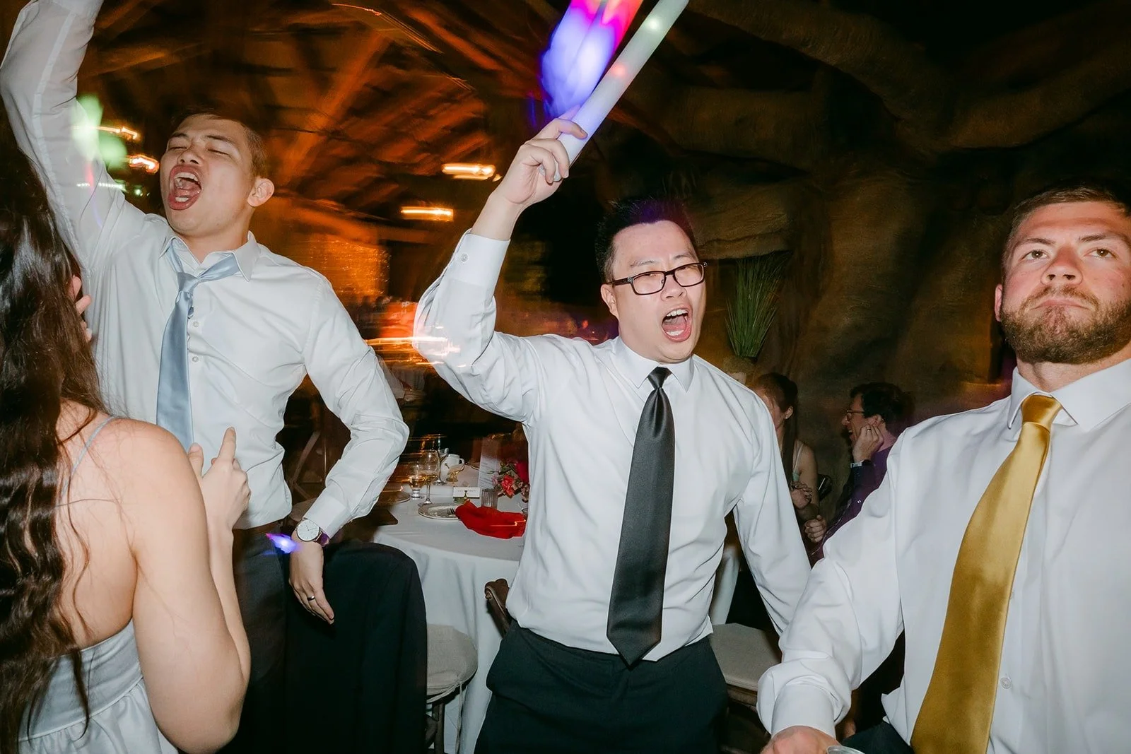 Groomsmen celebrating on the dance floor with a light stick