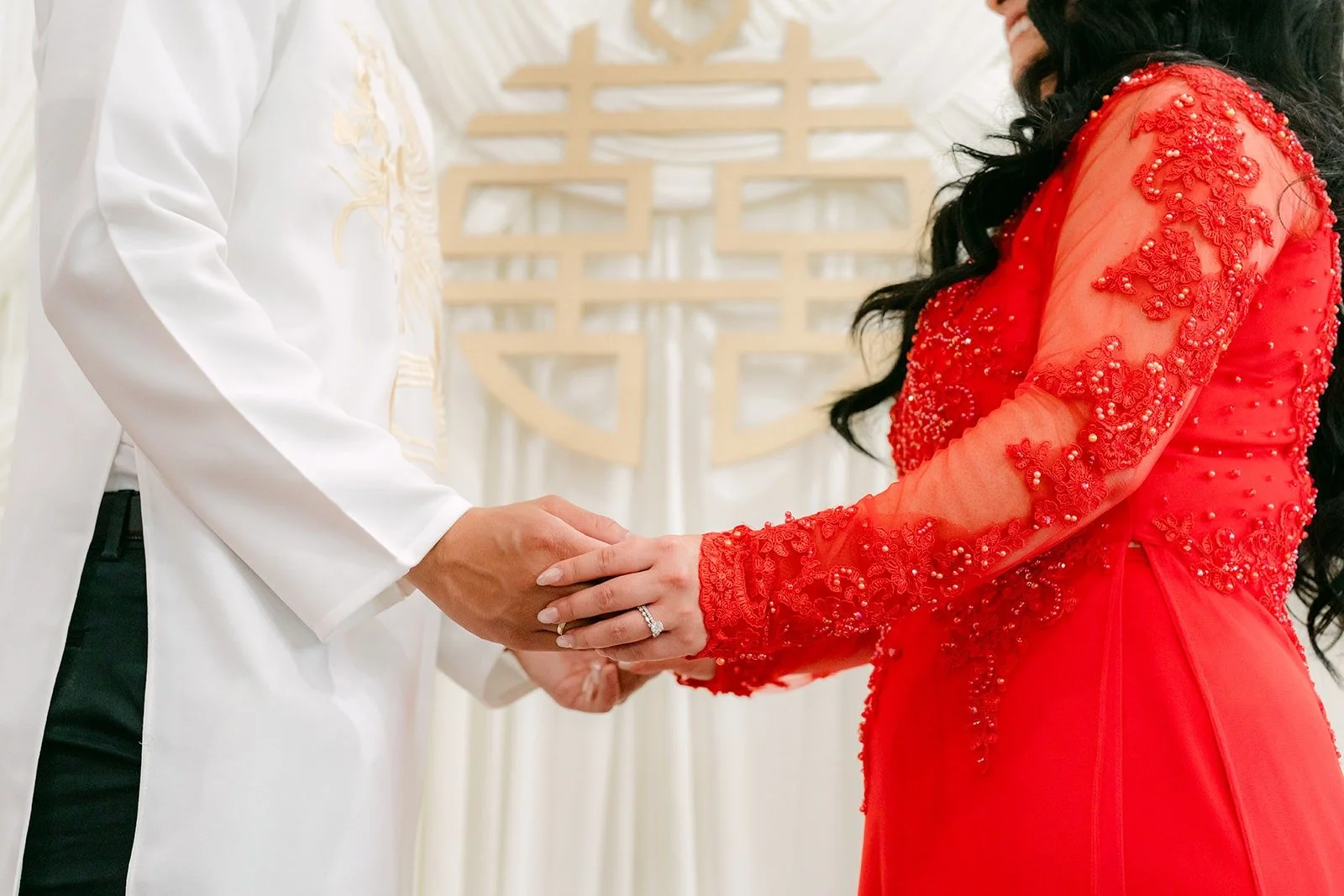 Jennifer and Kevin hold hands in front of the double happiness symbol