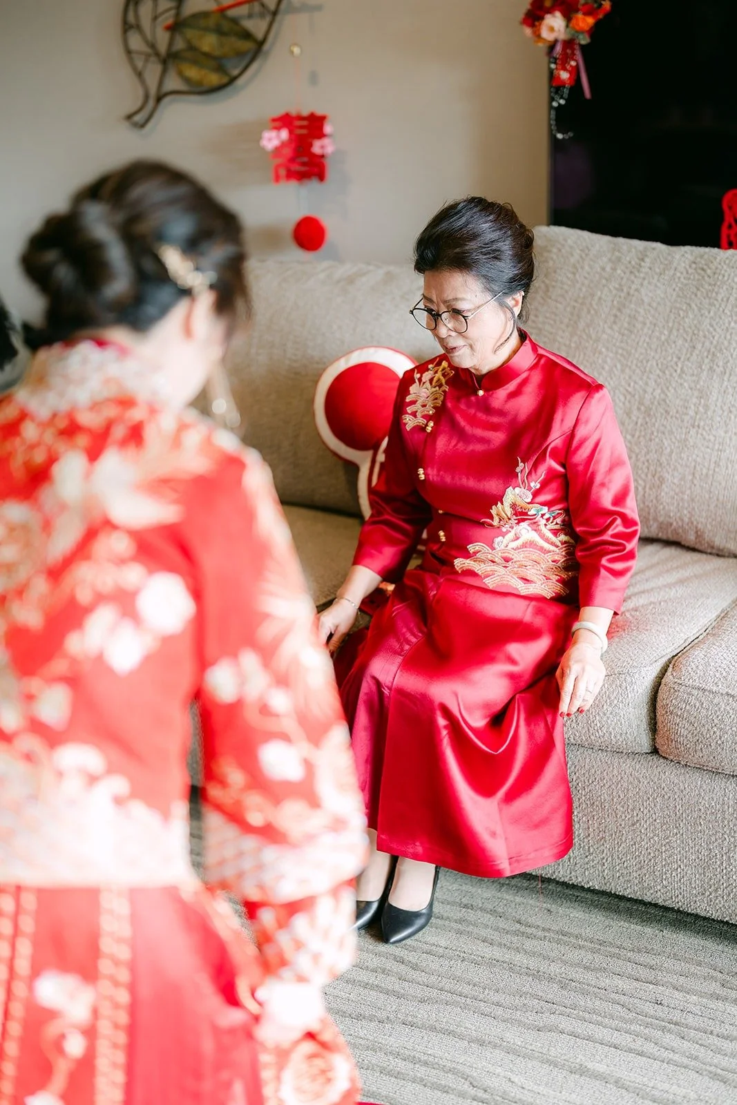 Sochi in her red and gold attire with a family member during the tea ceremony
