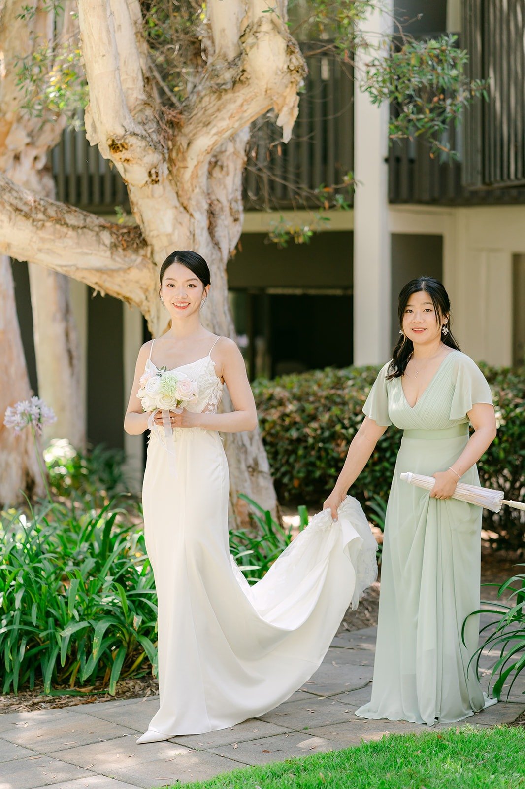 A bridesmaid carrying Tin's dress as she walks to the first look