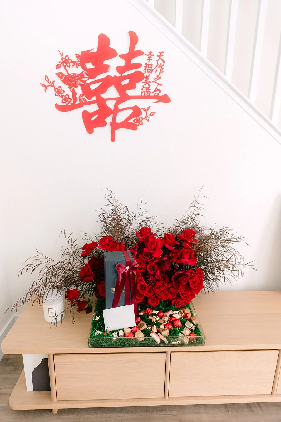 A double happiness papercut above a floral arrangement.